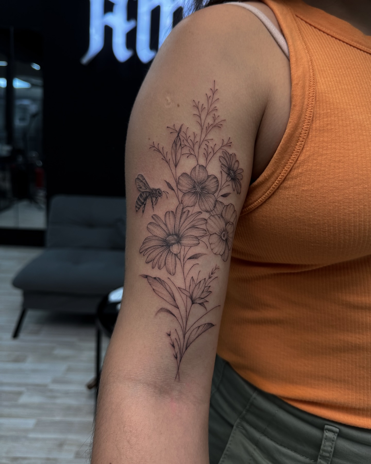 Floral arrangement with bee black and grey tattoo on the forearm by Nicolas Herrera