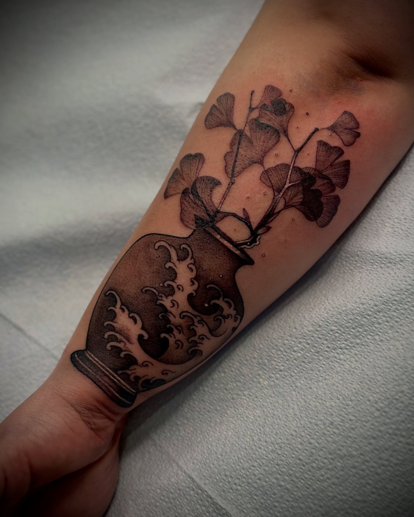 Vase with ginkgo leaves black and grey tattoo on the forearm by Feliz Manzanedo, Prescott, Arizona
