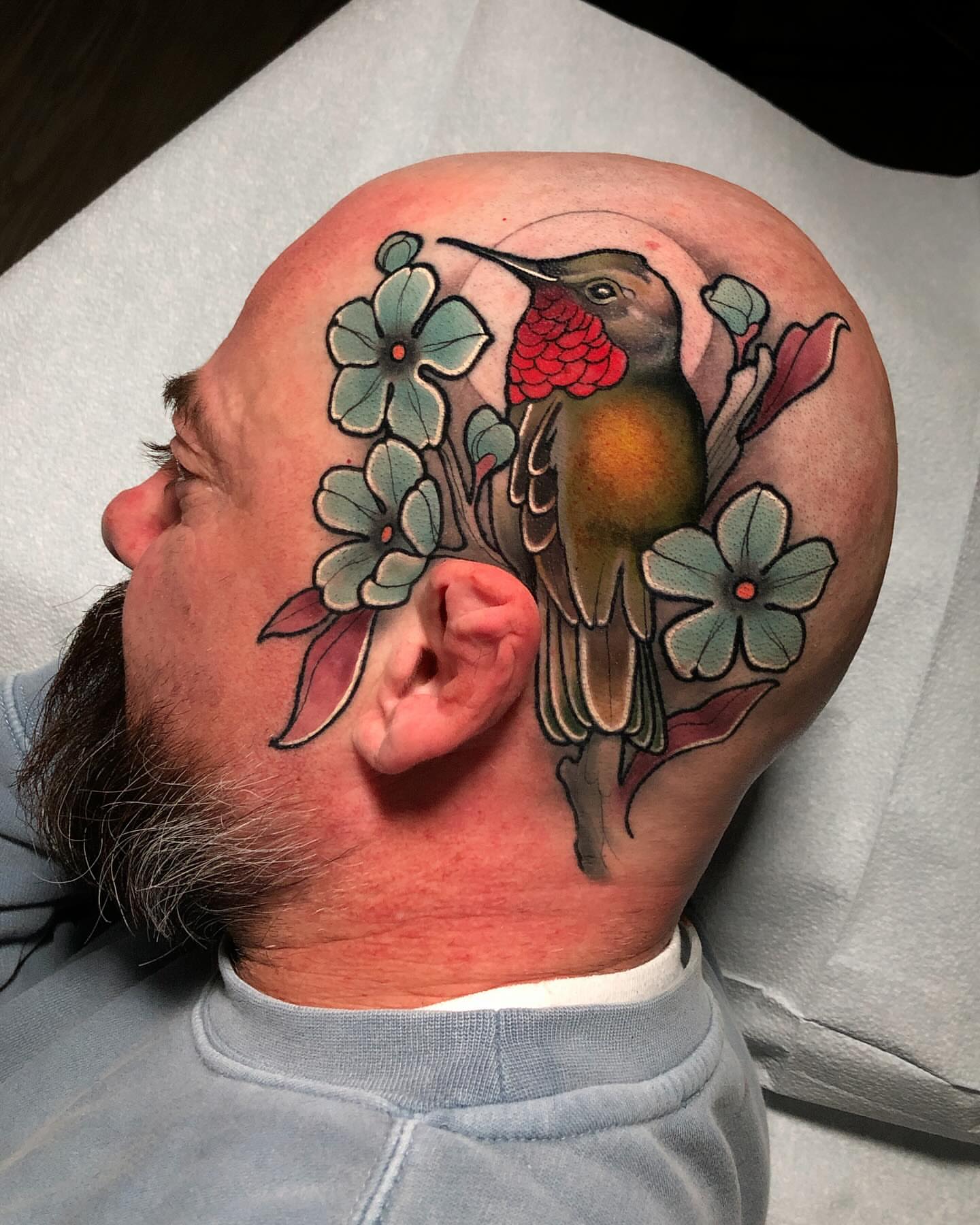 Hummingbird and flowers American traditional tattoo on the head by Milo Alfring Tattoo