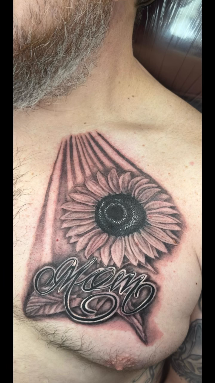 Sunflower with script "Mom" tattoo on the chest by Christian Colón, Nashville, Tennessee