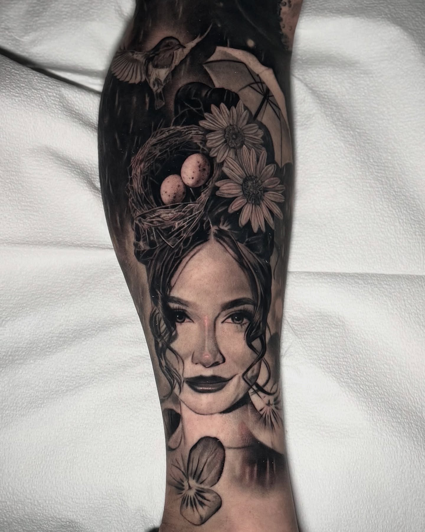 Woman's face with floral elements realism tattoo on the forearm by Caroline Yurek