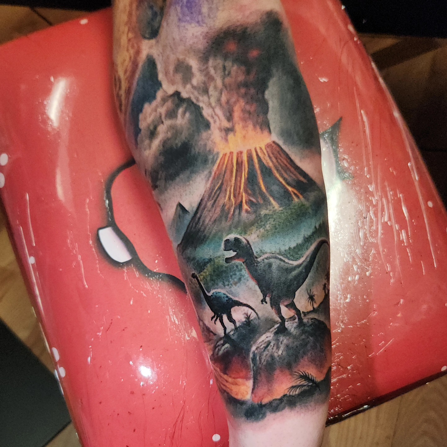 Volcano eruption with dinosaurs realism tattoo on the forearm by Don Taylor