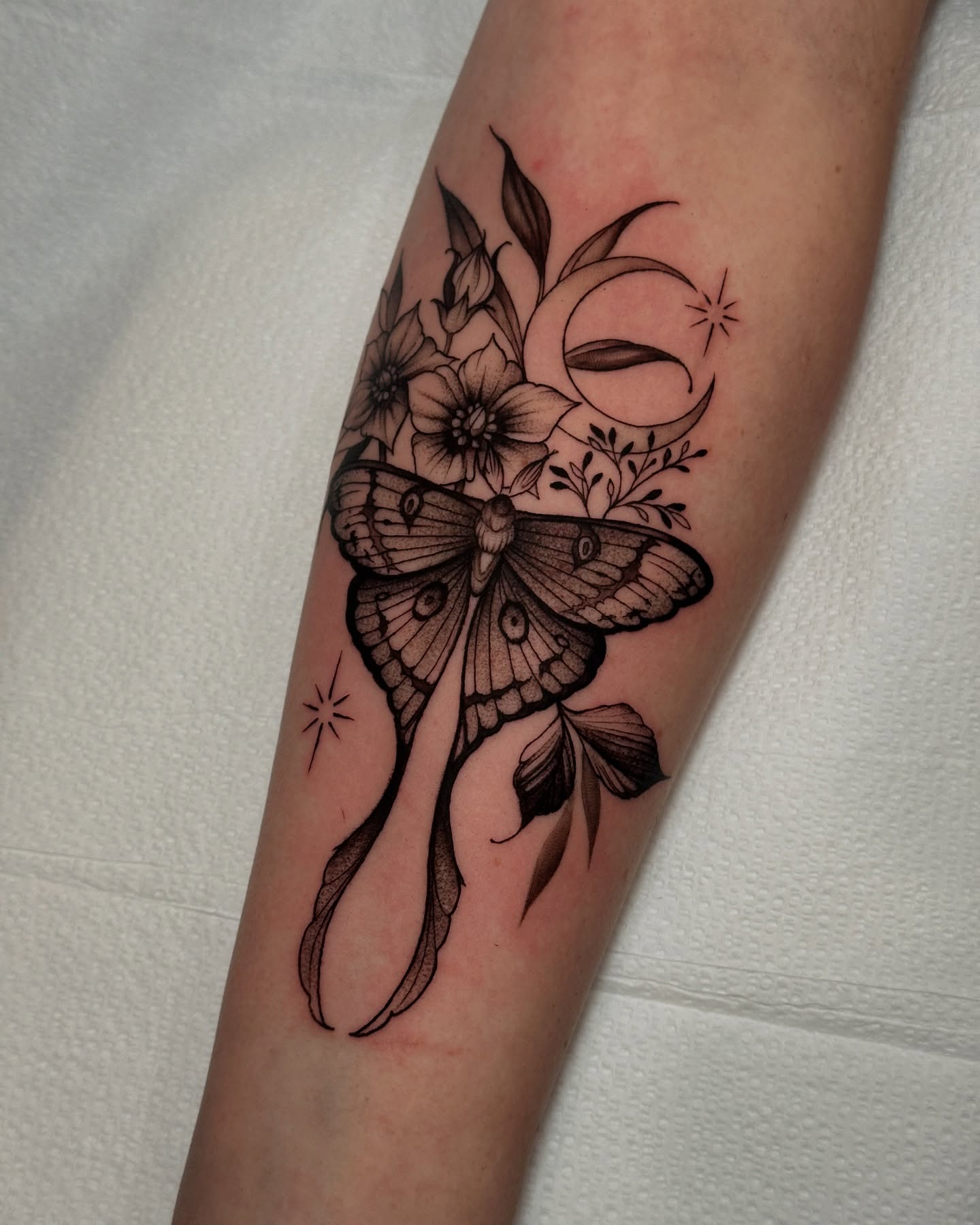 Butterfly and flowers realism tattoo on the forearm by Macayla Myers