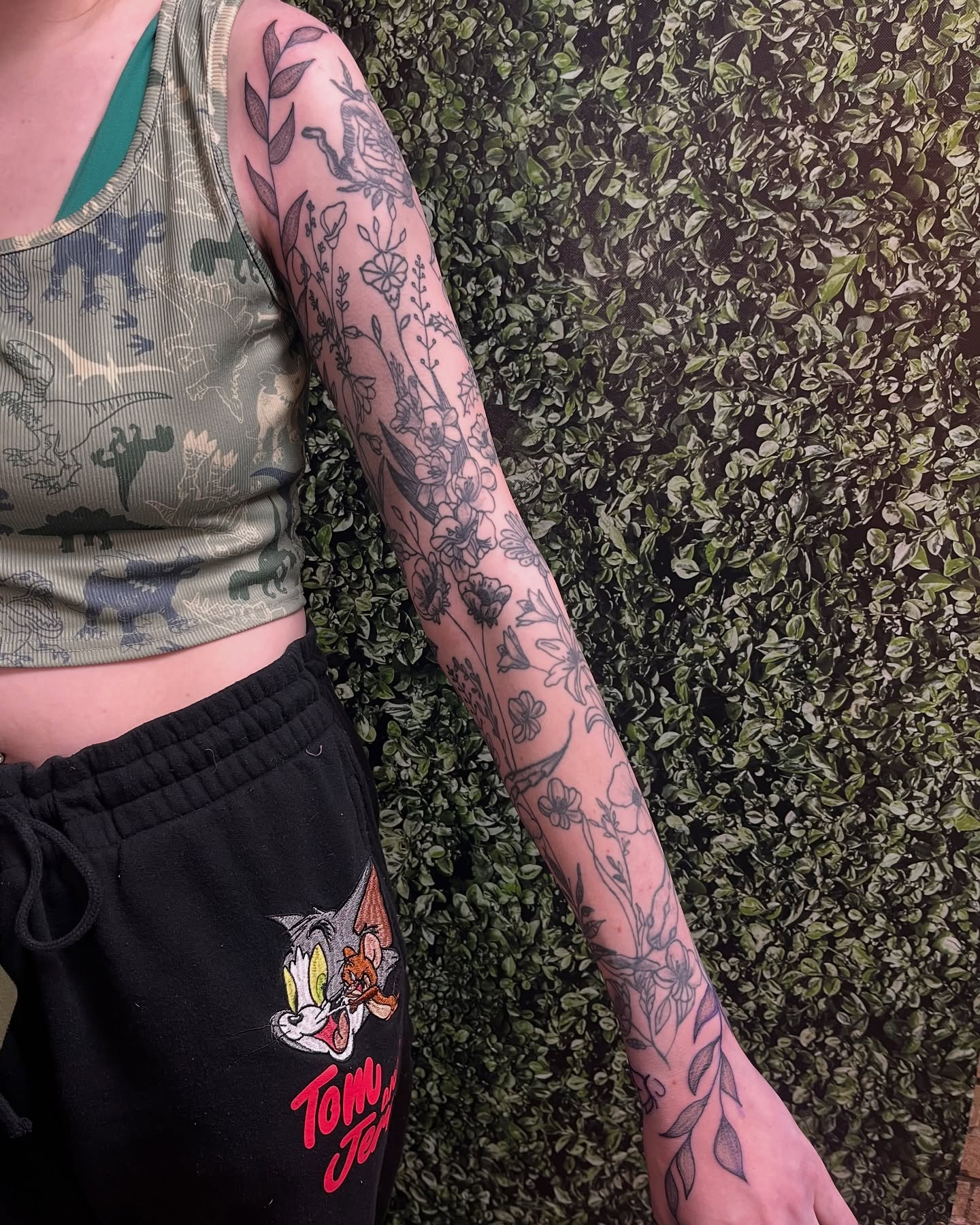 Floral and botanical black and grey tattoo on the upper arm by Michelle