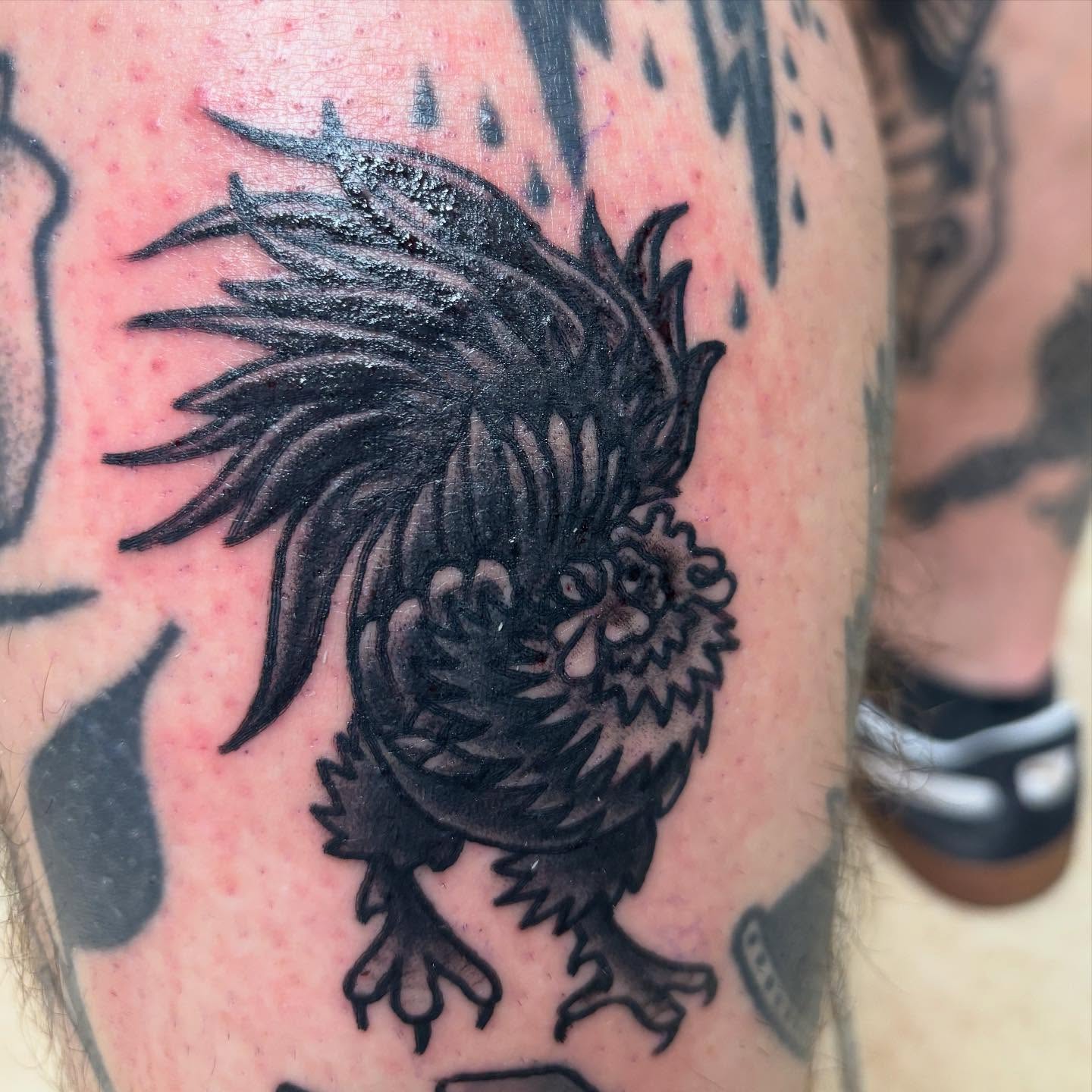 Rooster black and grey tattoo on the upper arm by Oscar Cuéllar (Kue-Yar)