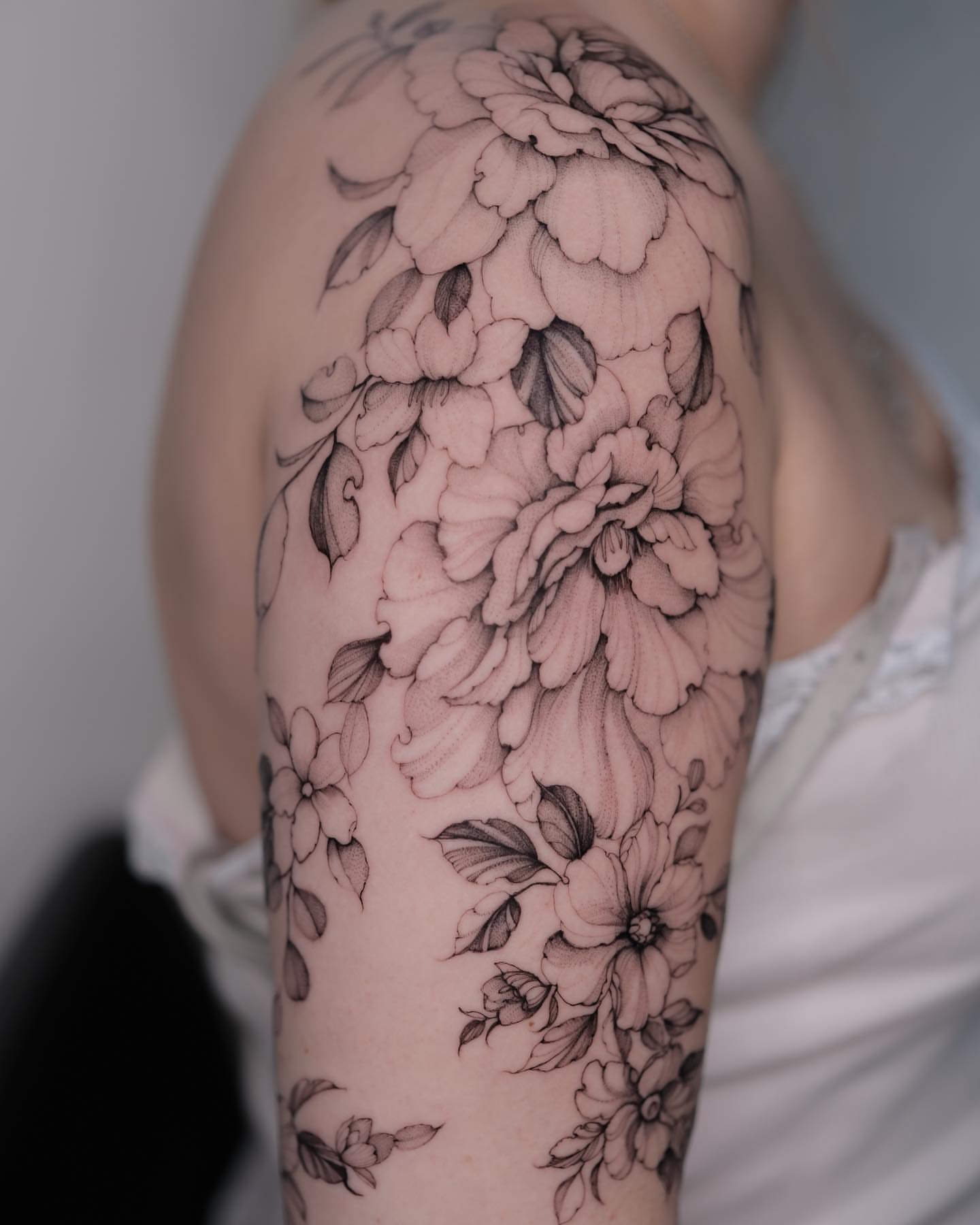 Floral bouquet black and grey tattoo on the upper arm by Tattoo artist in Boston