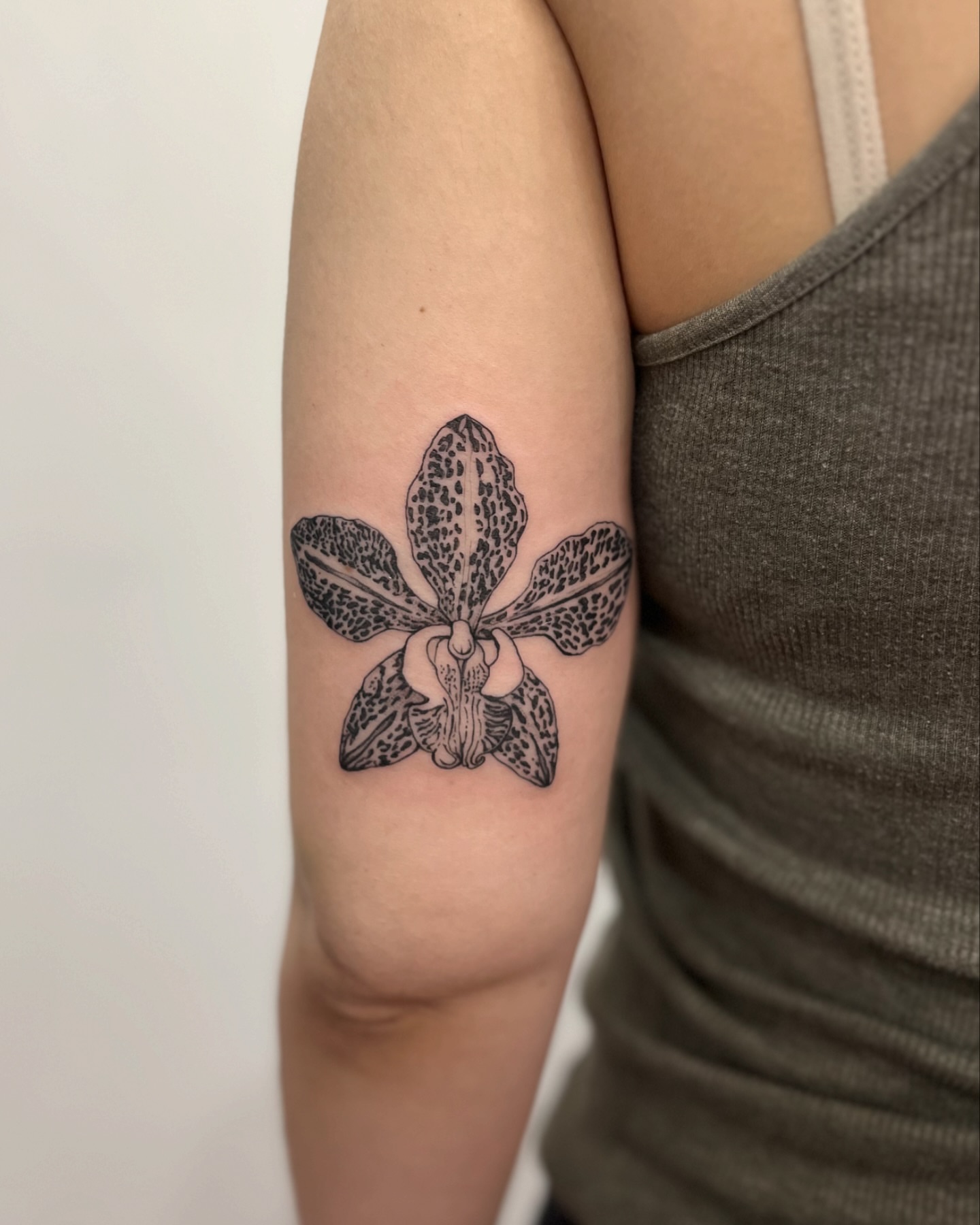 Orchid black and grey tattoo on the forearm by Ying Xeon
