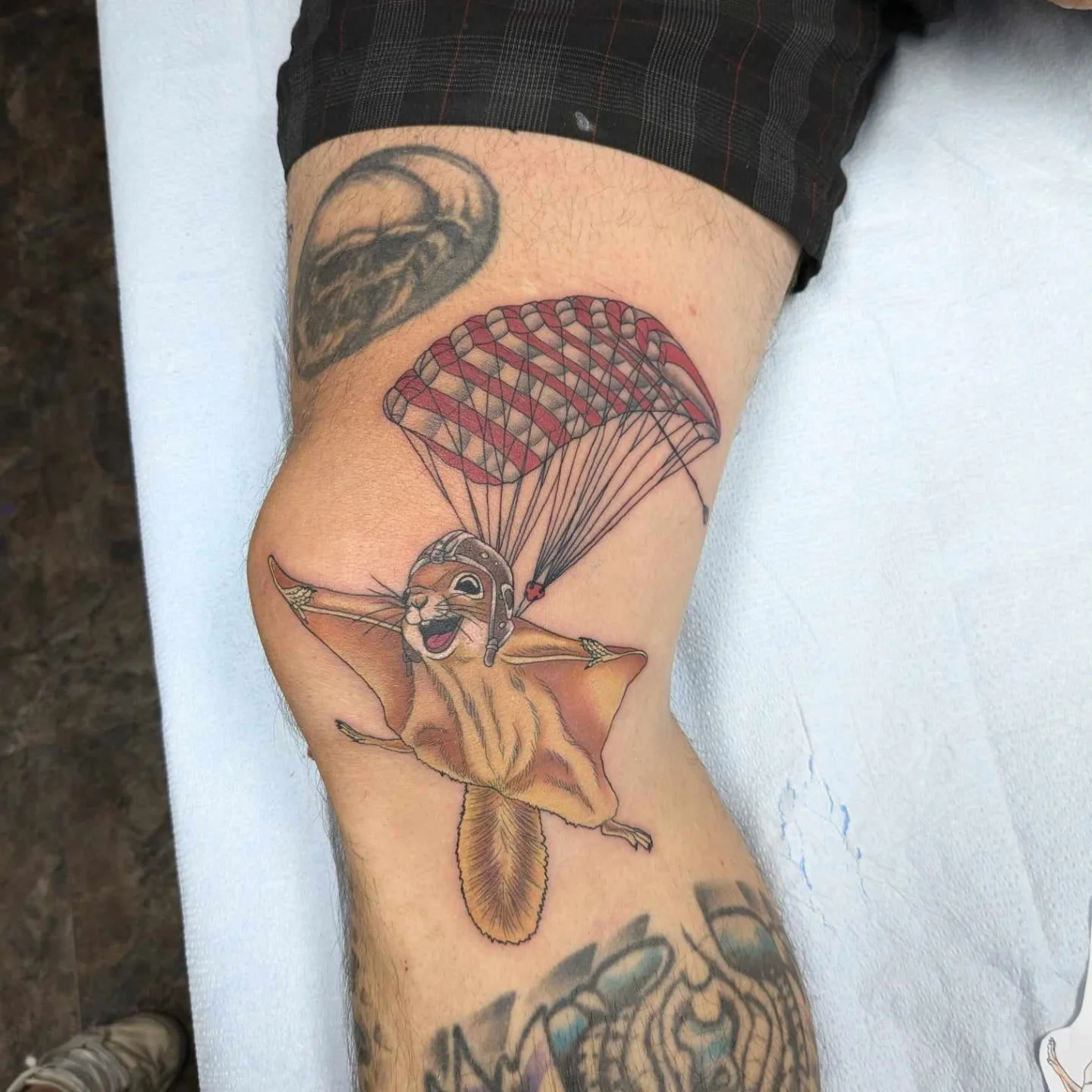 Parachuting squirrel illustrative tattoo on the thigh by Kara Falcon