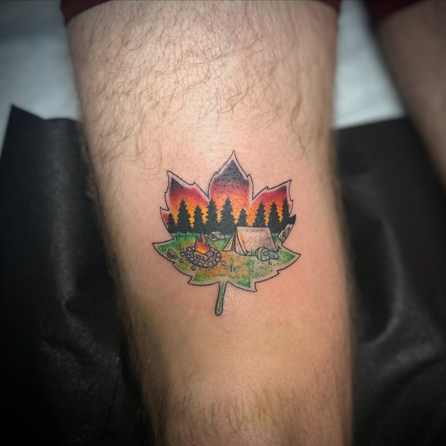 Maple leaf with campfire and tent American traditional tattoo on the forearm by Savy Rasor, Austin, Texas