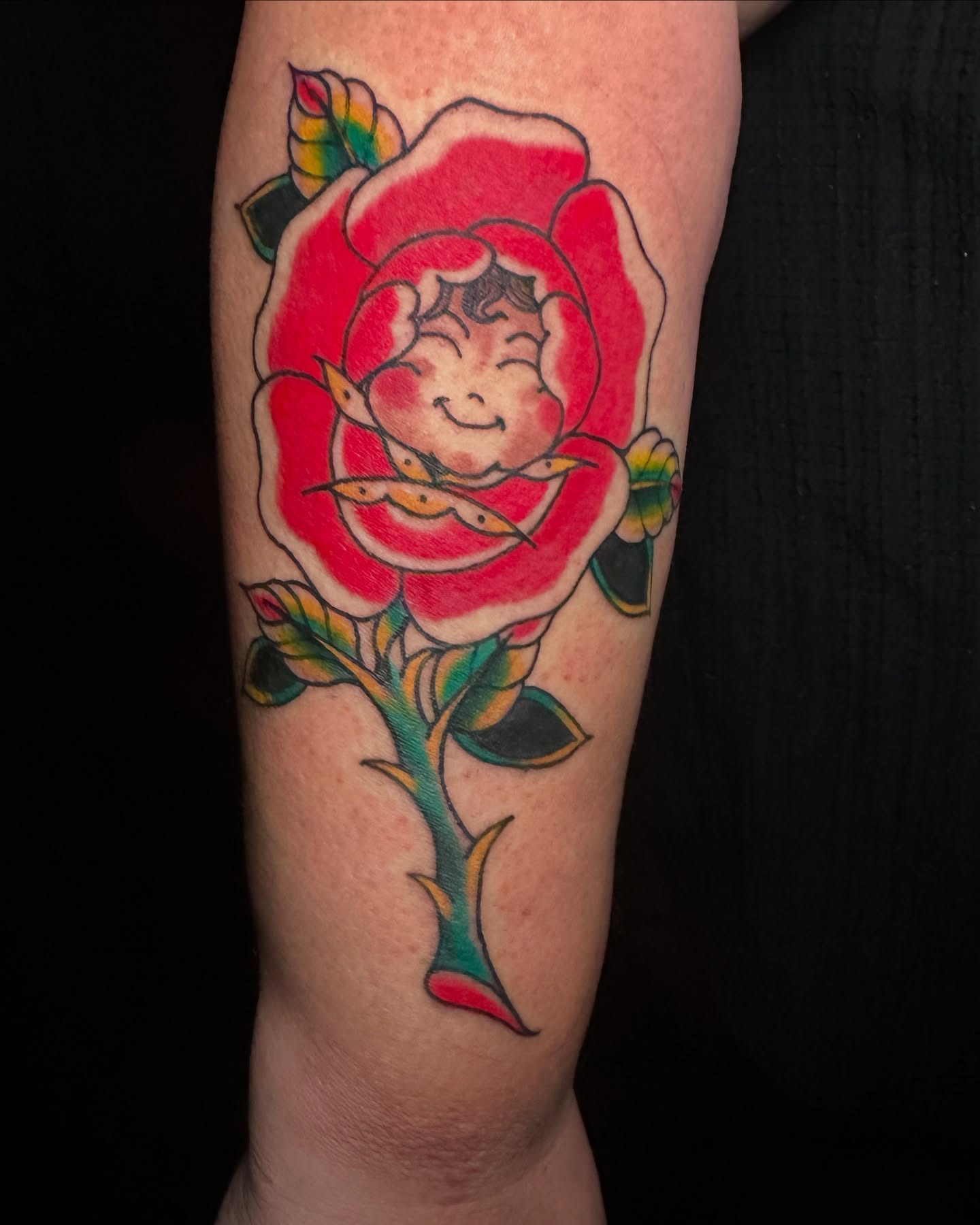 Rose with smiling face American traditional tattoo on the forearm by vannadoestattoos