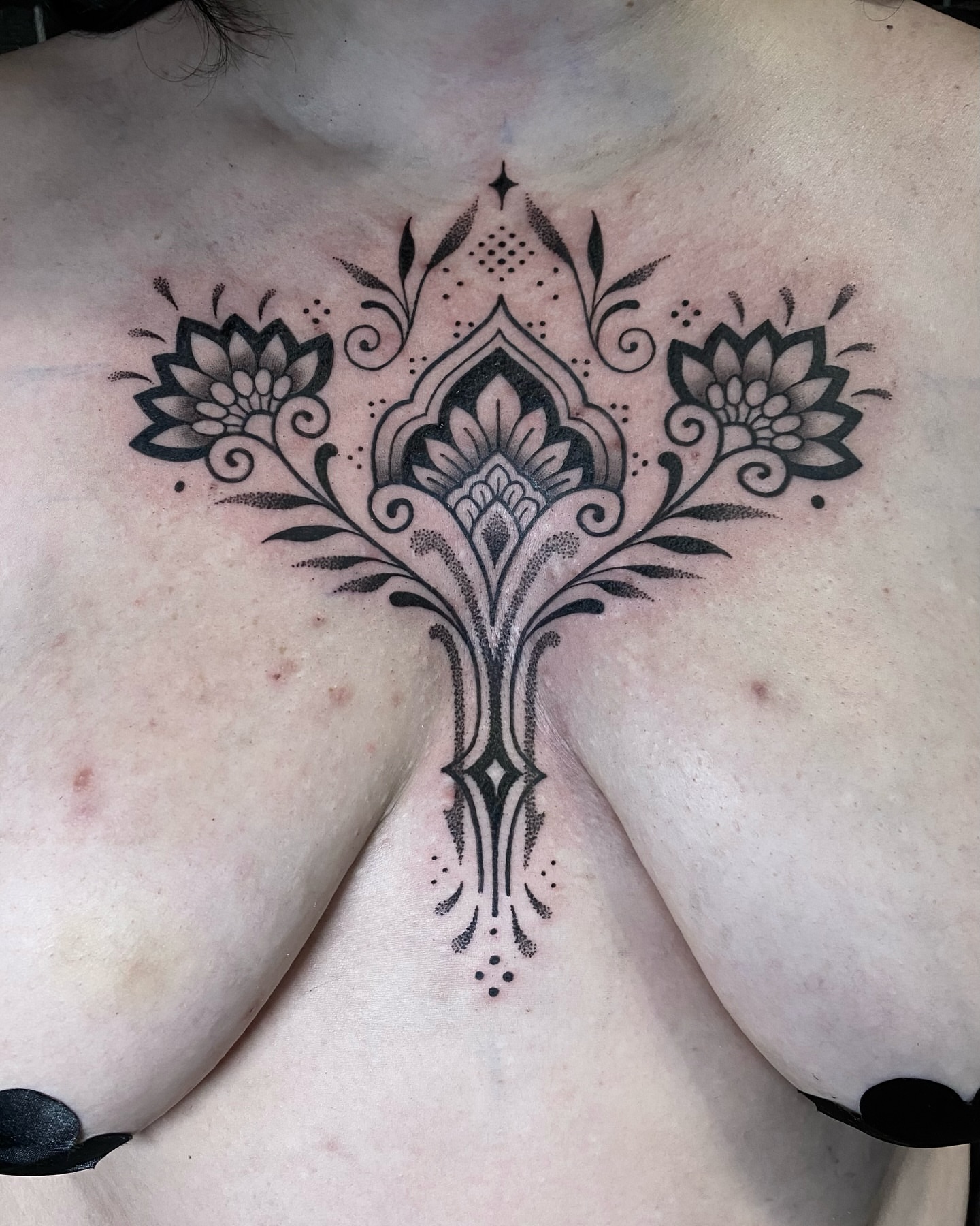 Lotus flowers and ornamental design dotwork tattoo on the chest by Rose Ulinski