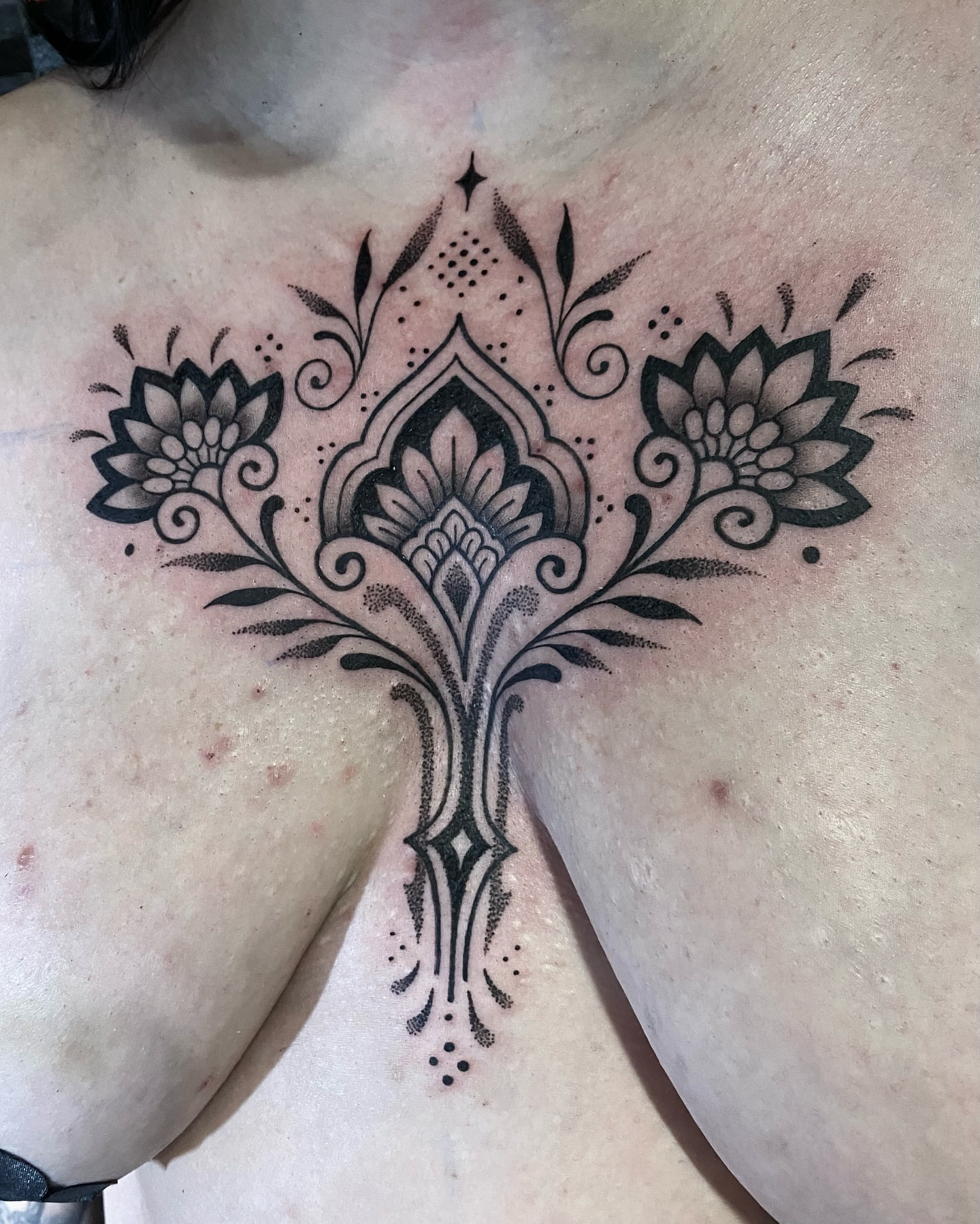 Floral ornament dotwork tattoo on the chest by Rose Ulinski