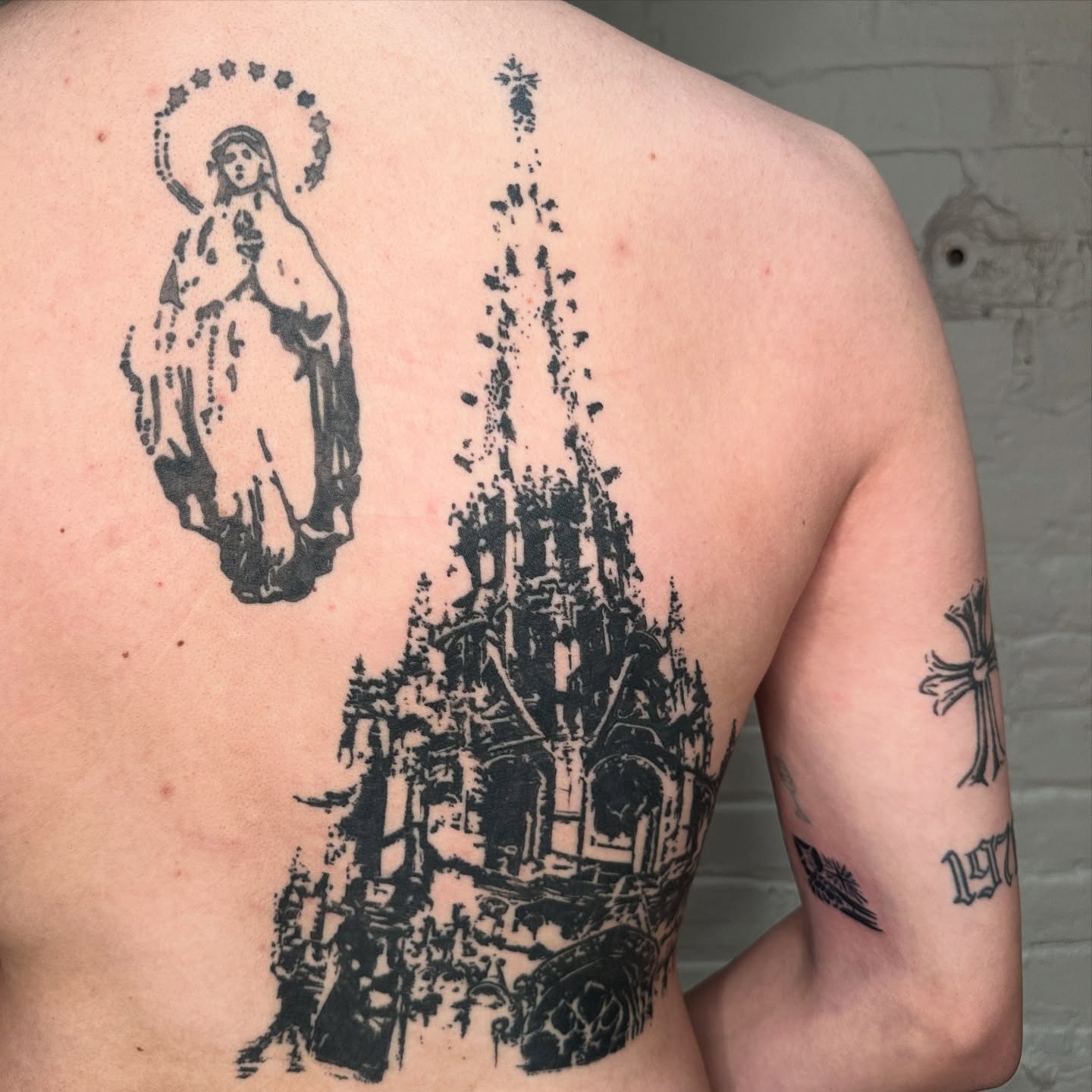 Religious figure and cathedral black and grey tattoo on the back by πΈππππππ