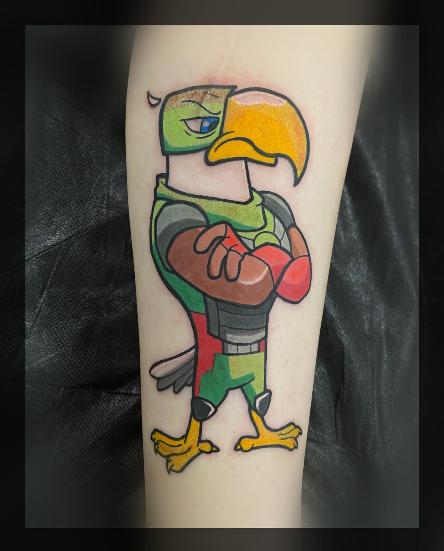 Bird holding football new school tattoo on the forearm by Romans