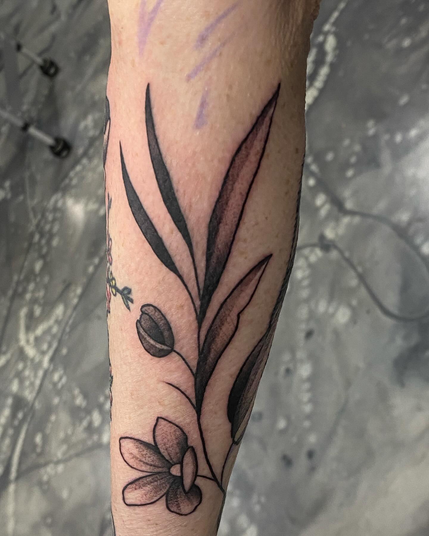 Flower and leaf black and grey tattoo on the forearm by Romans