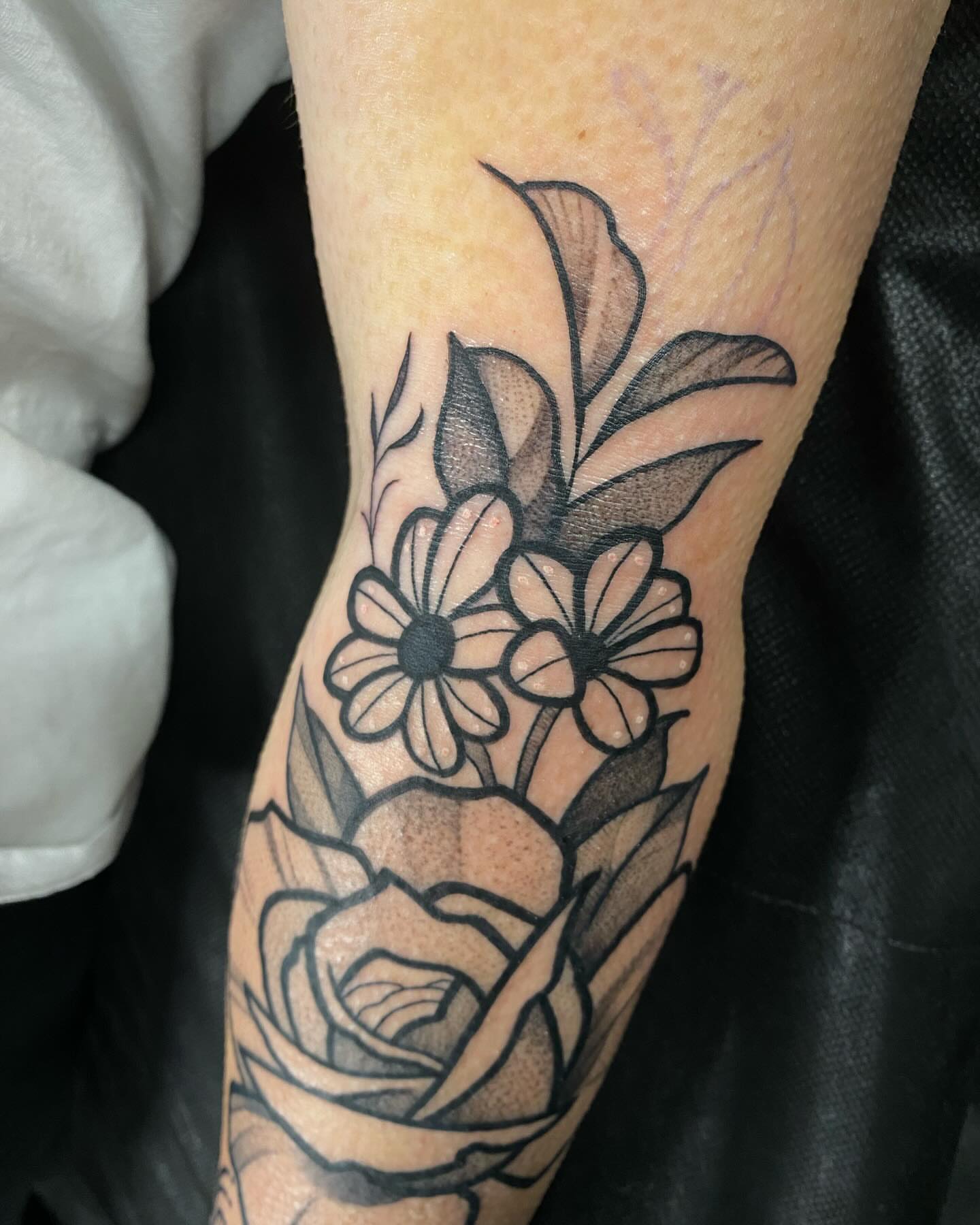 Floral arrangement black and grey tattoo on the forearm by Romans