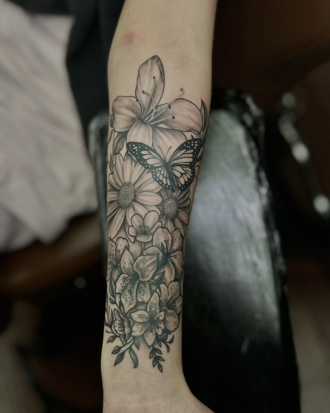 Flowers and butterfly black and grey tattoo on the forearm by James Reed Tattoo artist