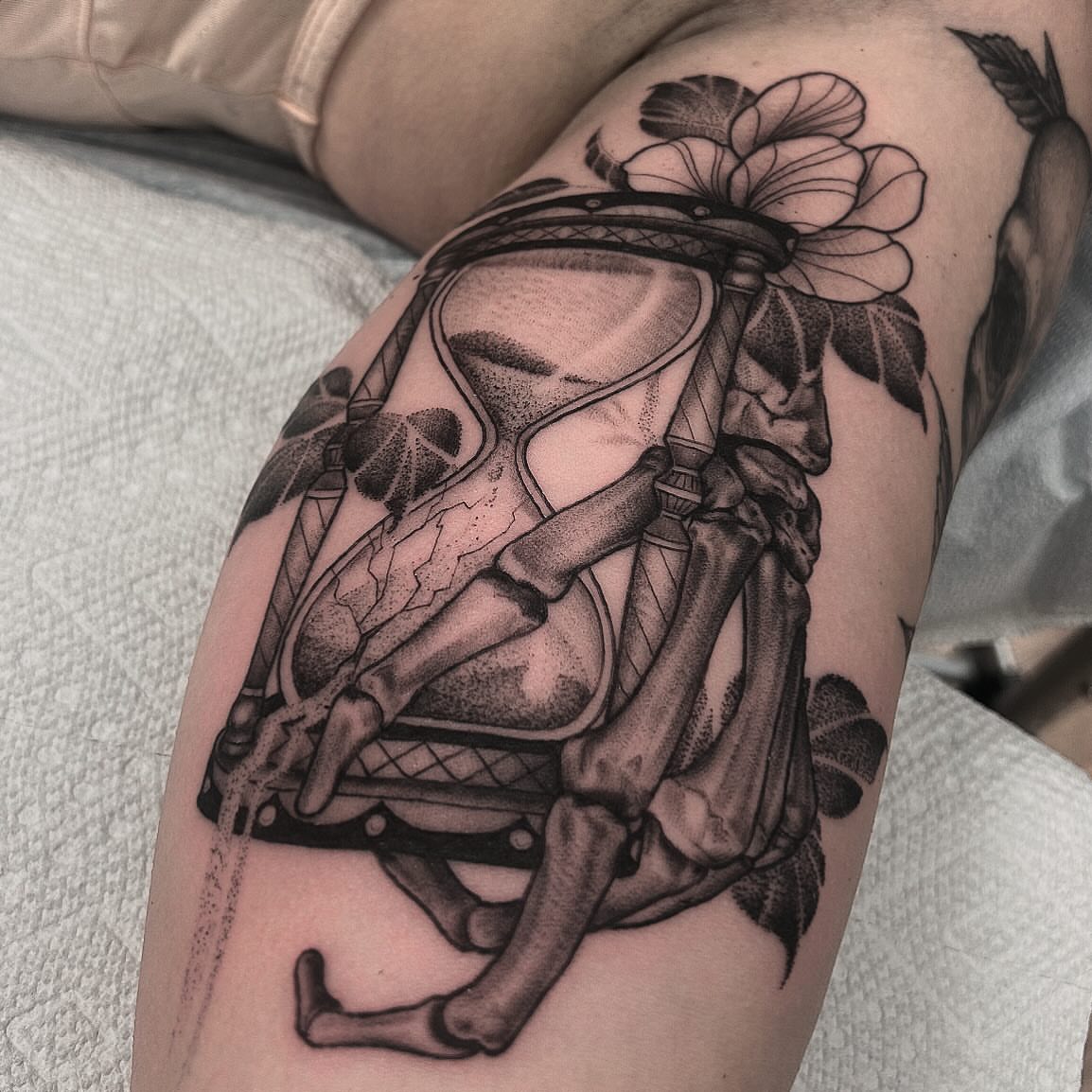 Hourglass and flower dotwork tattoo on the thigh by Pat Moser