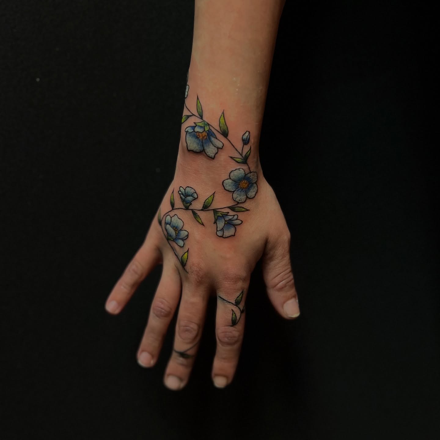 Blue flowers watercolor tattoo on the hand by Stevie Reign