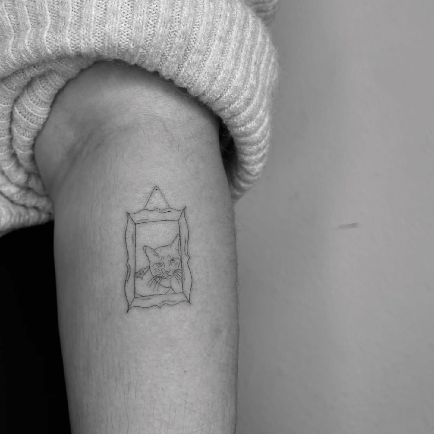 Cat in mirror minimalist tattoo on the forearm by Mady