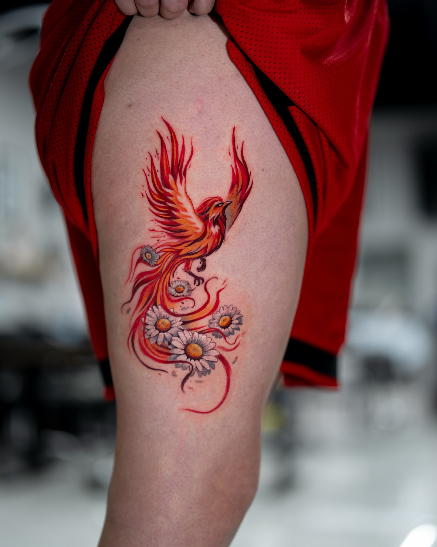 Phoenix and daisies watercolor tattoo on the thigh by Joey Hella Tattoo Artist