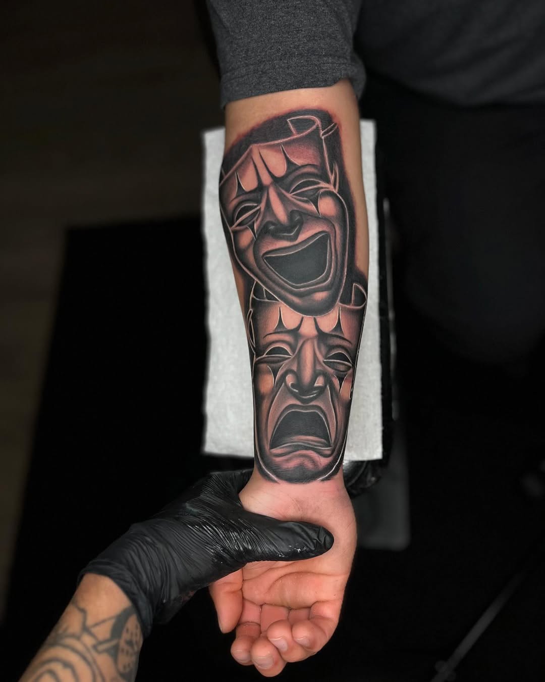 Comedy and tragedy masks realism tattoo on the forearm by Tattoo Artist