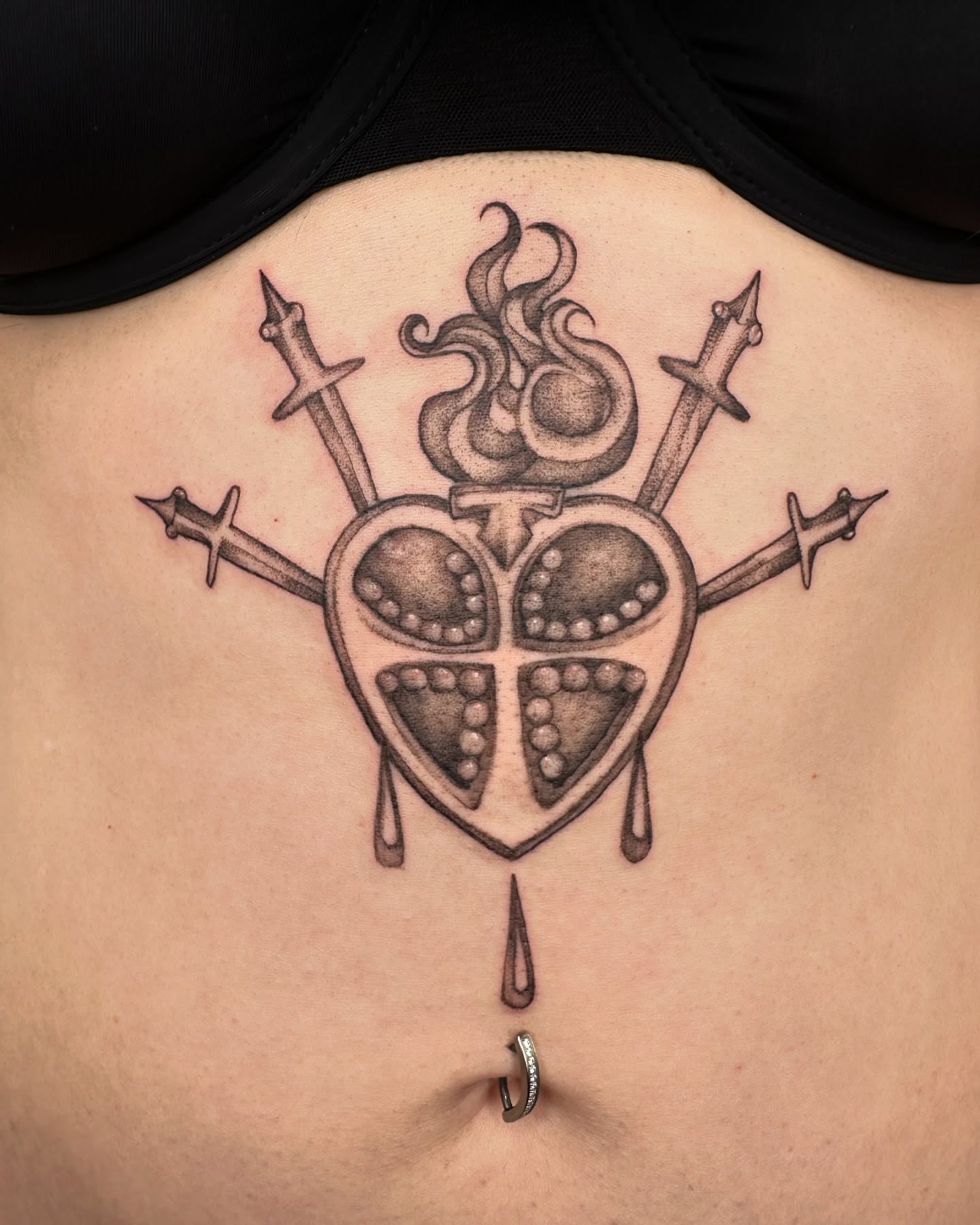 Heart with flames and swords dotwork tattoo on the torso by cora cupid