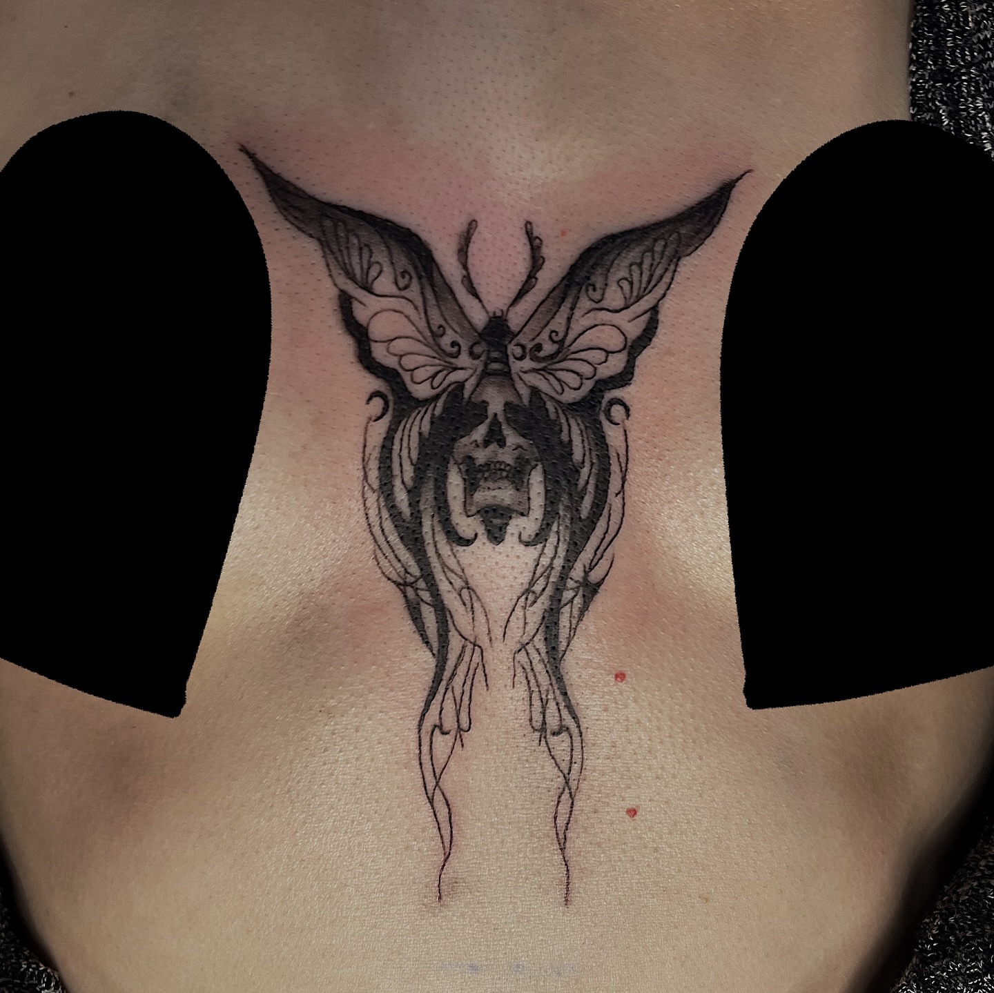 Skull with butterfly dark realism tattoo on the chest by Nikki Ward