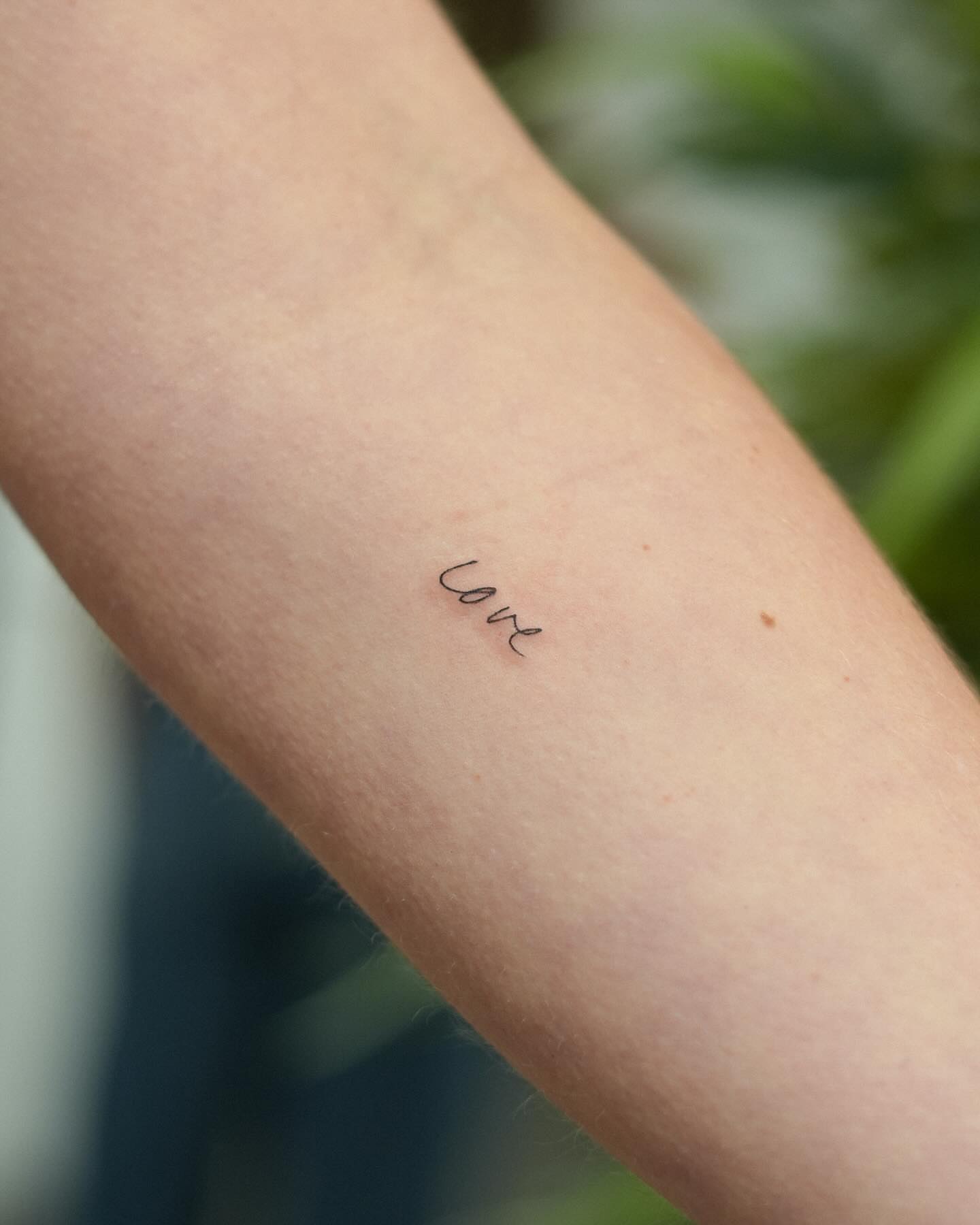 Love lettering script tattoo on the forearm by Adriano Bassalo