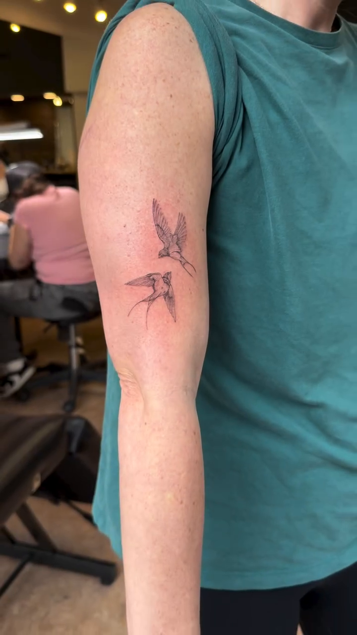 Two swallows in flight fine line tattoo on the forearm by Chanel Picquelle, Nashville, Tennessee