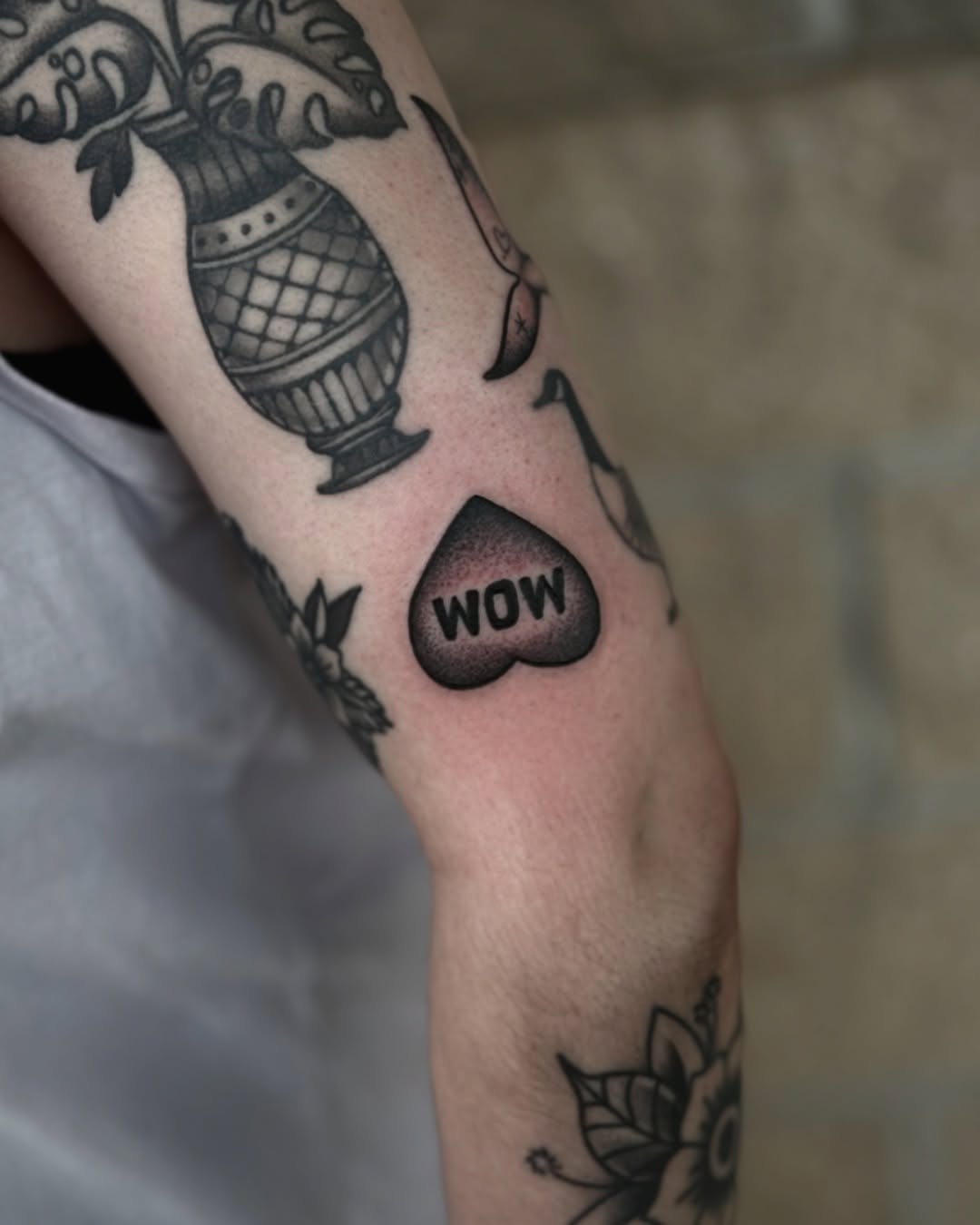 Heart with 'WOW' black and grey tattoo on the forearm by K9