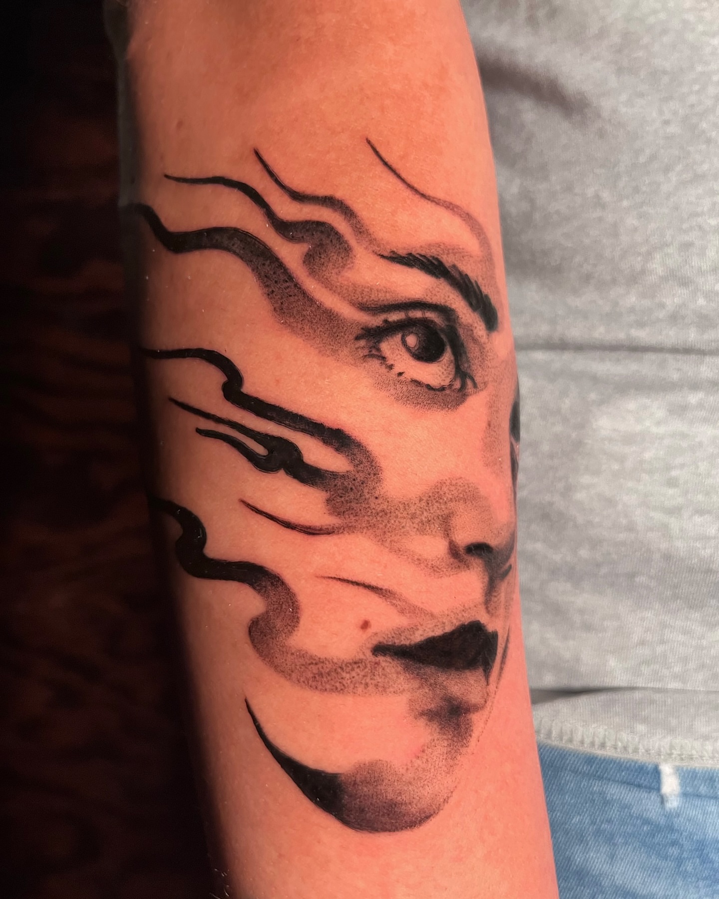 Face with swirling lines dotwork tattoo on the forearm by "el asere, el zurdo"