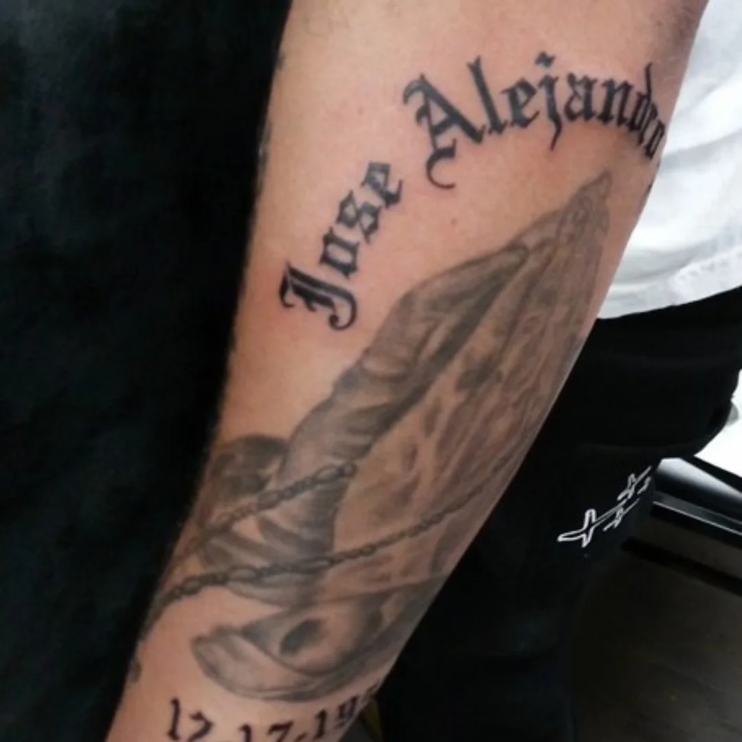 Praying hands black and grey tattoo on the forearm by Cassandra Davis