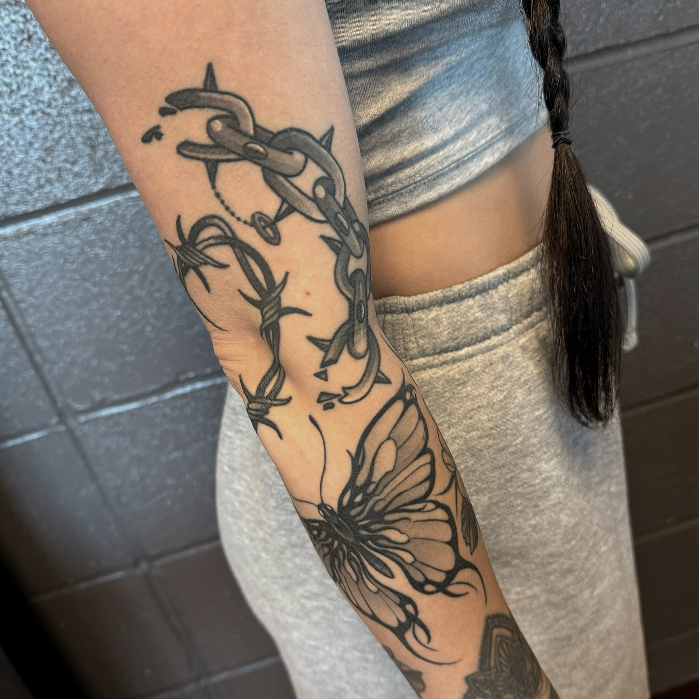Chain and butterfly black and grey tattoo on the forearm by Anne Cornelson