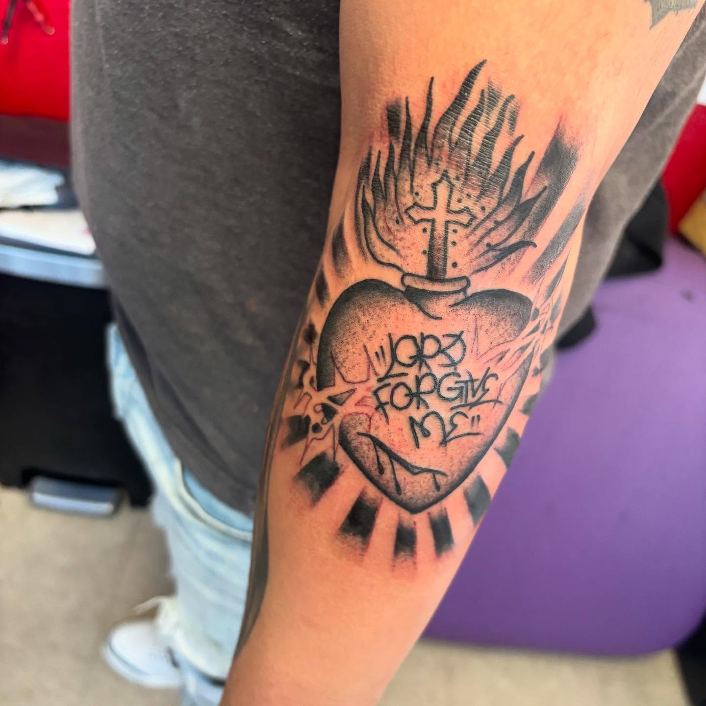 Heart with cross black and grey tattoo on the forearm by 18 and older High End Tattoo