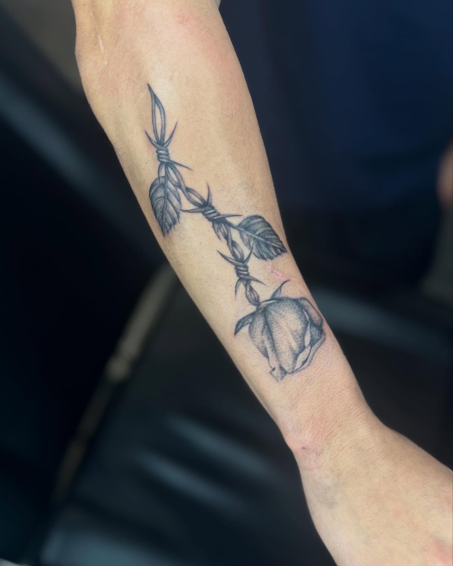 Barbed wire and rose black and grey tattoo on the forearm by Alexa Camacho