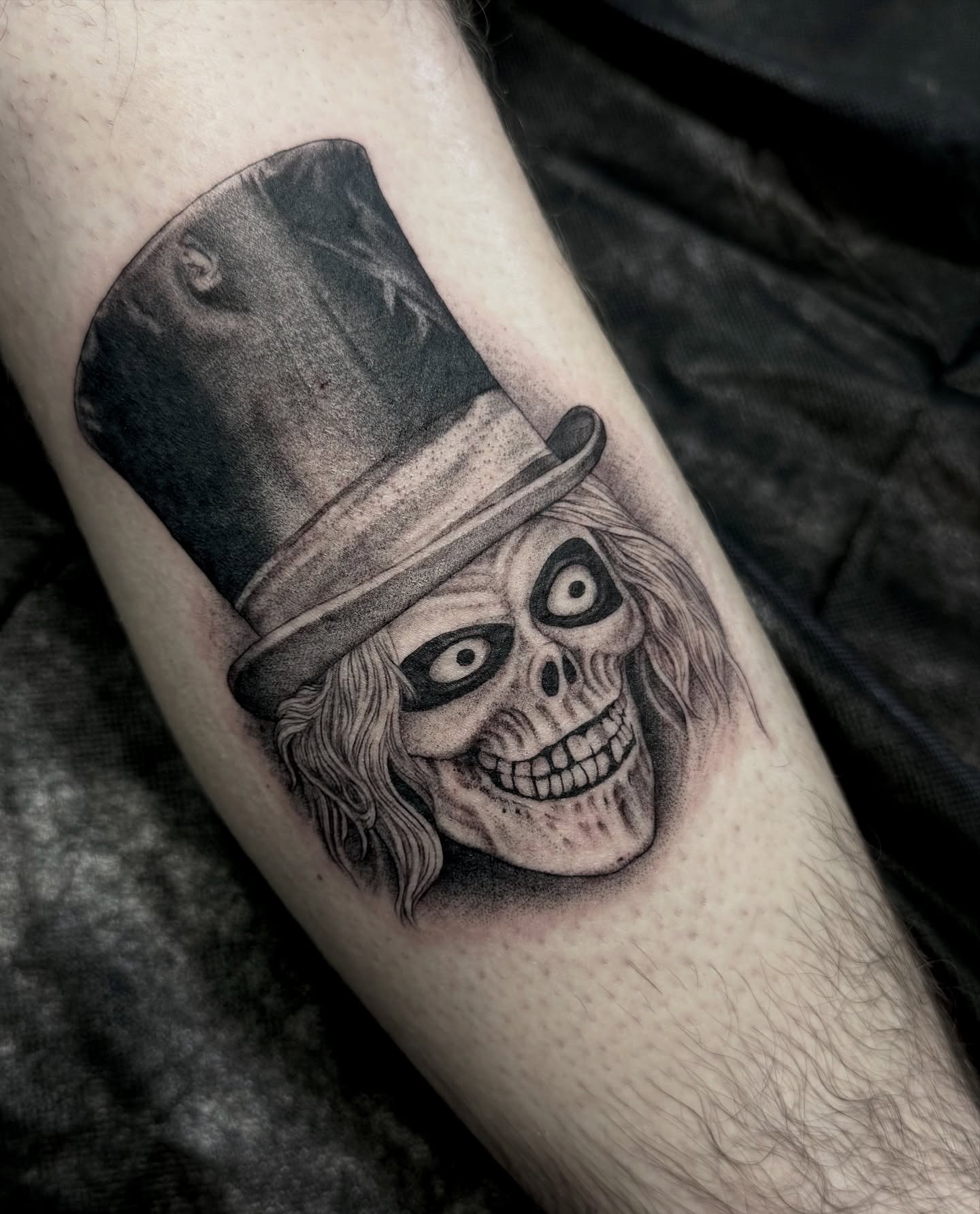 Skull wearing top hat realism tattoo on the forearm by Ernie Rivera