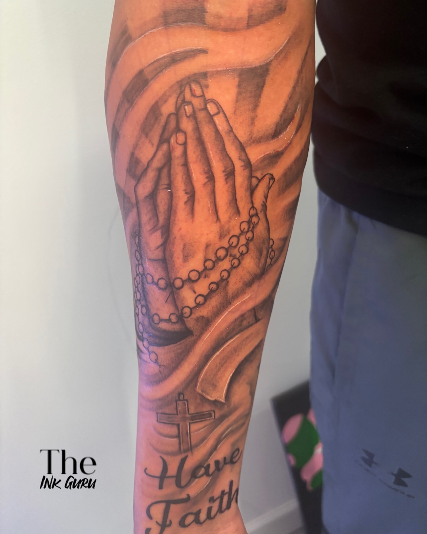 Praying hands with rosary realism tattoo on the forearm by The Ink Guru.