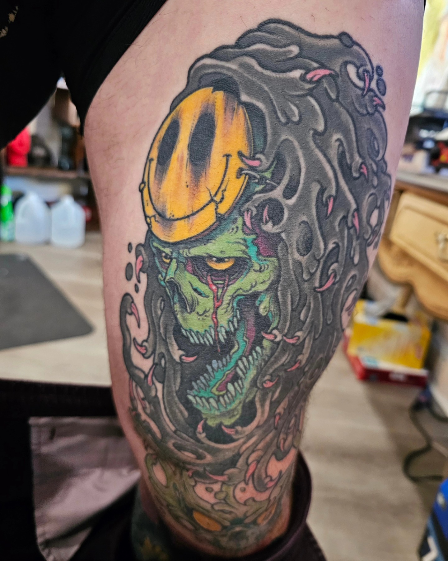 Smiley face monster new school tattoo on the thigh by Shannon