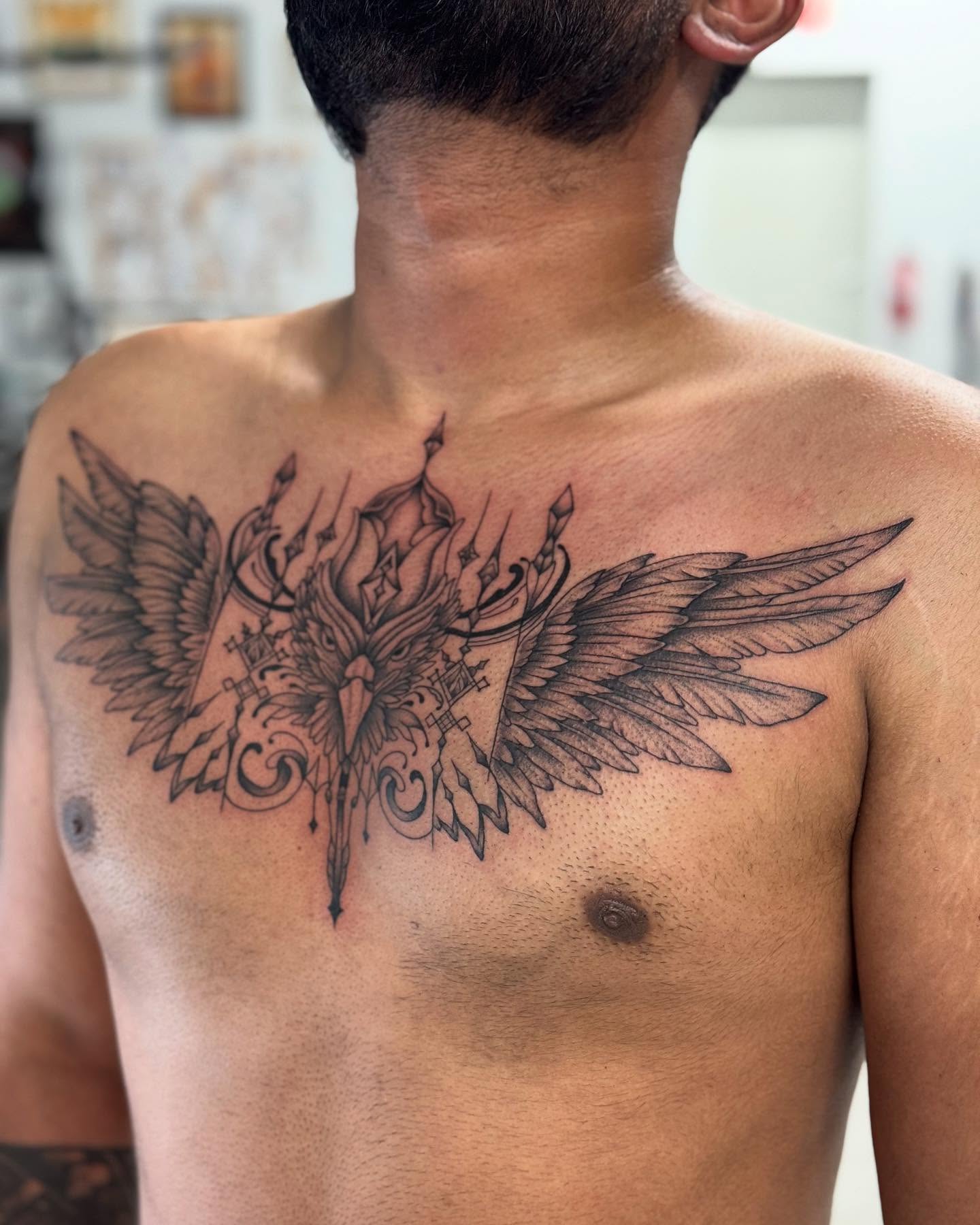 Wings and ornate design geometric tattoo on the chest by Cory Perry-Servellon
