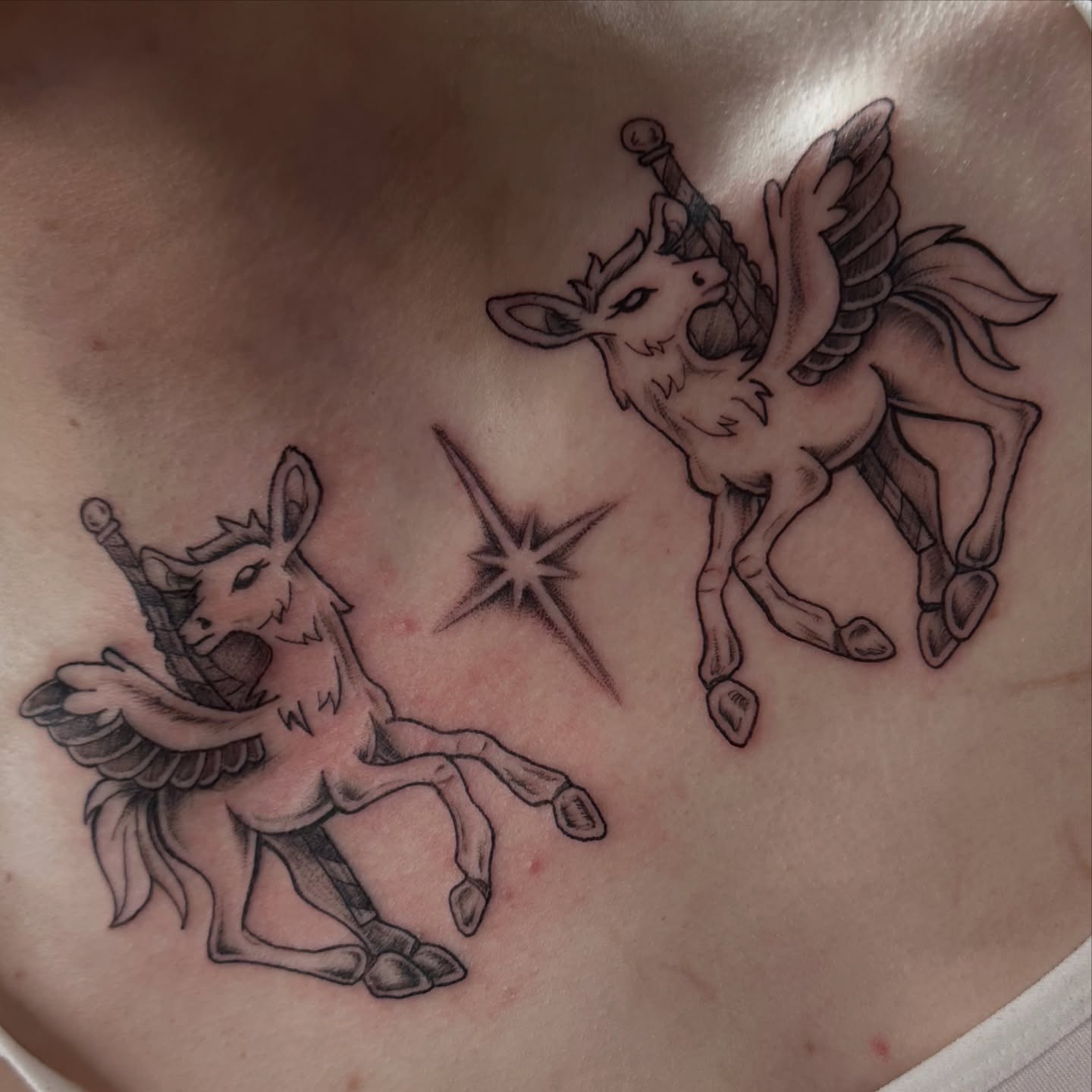 Unicorns and stars black and grey tattoo on the chest by Emily K Lingg