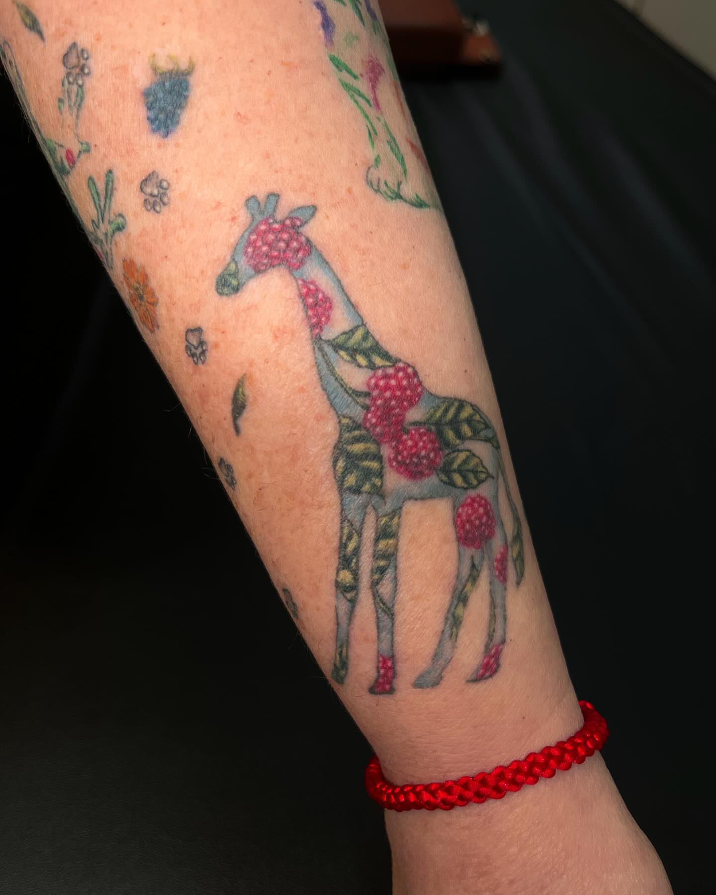 Giraffe with berries dotwork tattoo on the forearm by Katlyne Jones