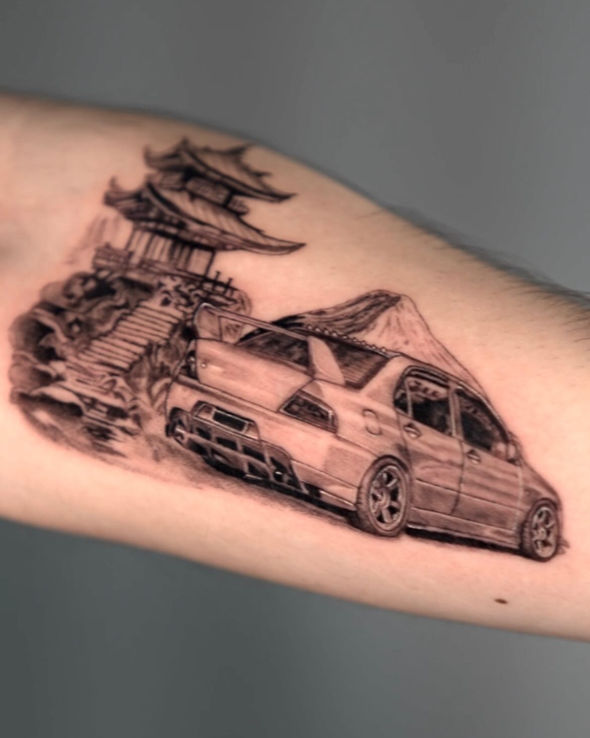 Japanese-style building and car realism tattoo on the forearm by Anthony “Jiinky” Quintanilla 🧸☁️