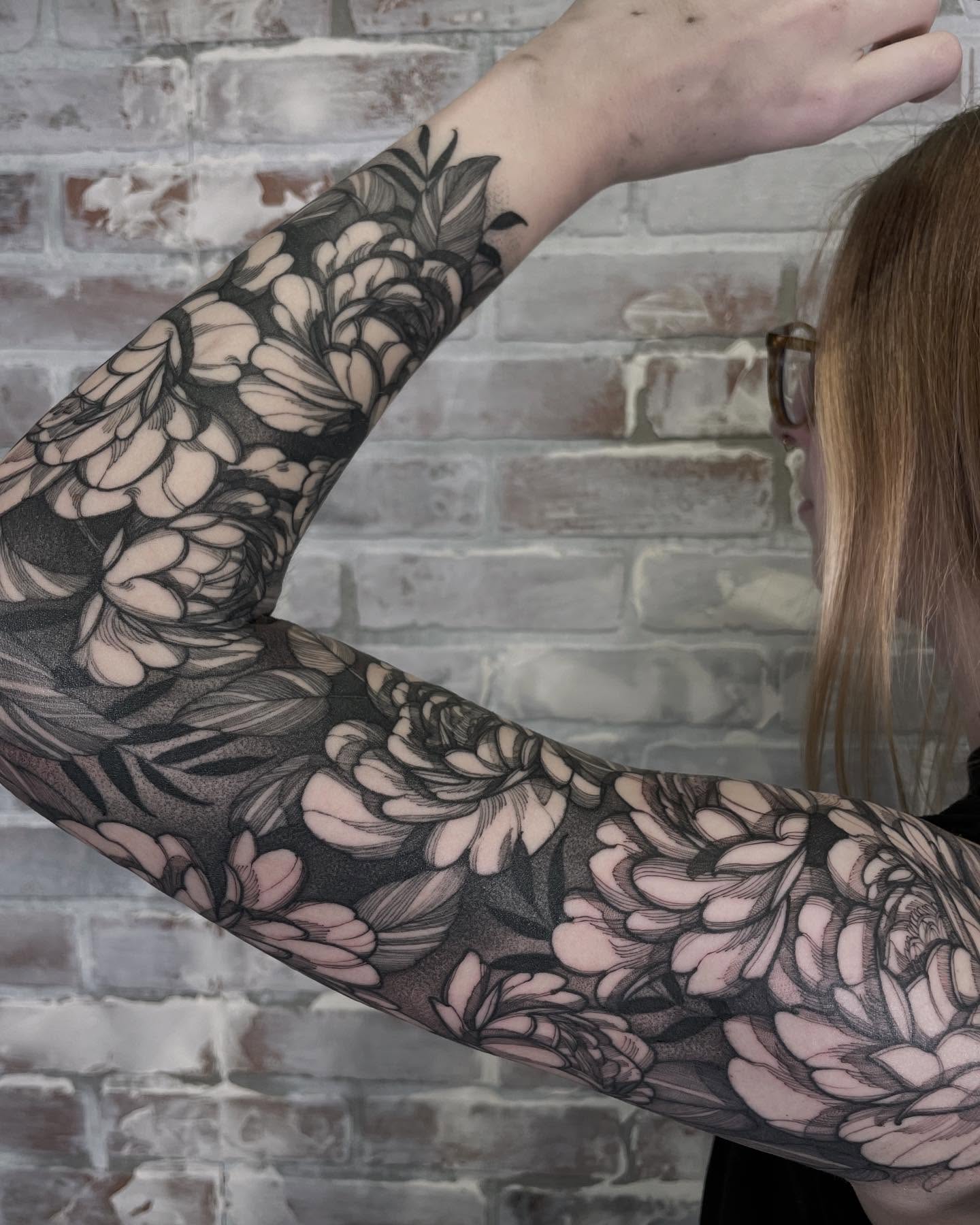 Floral sleeve black and grey tattoo on the upper arm by Carol Jacky