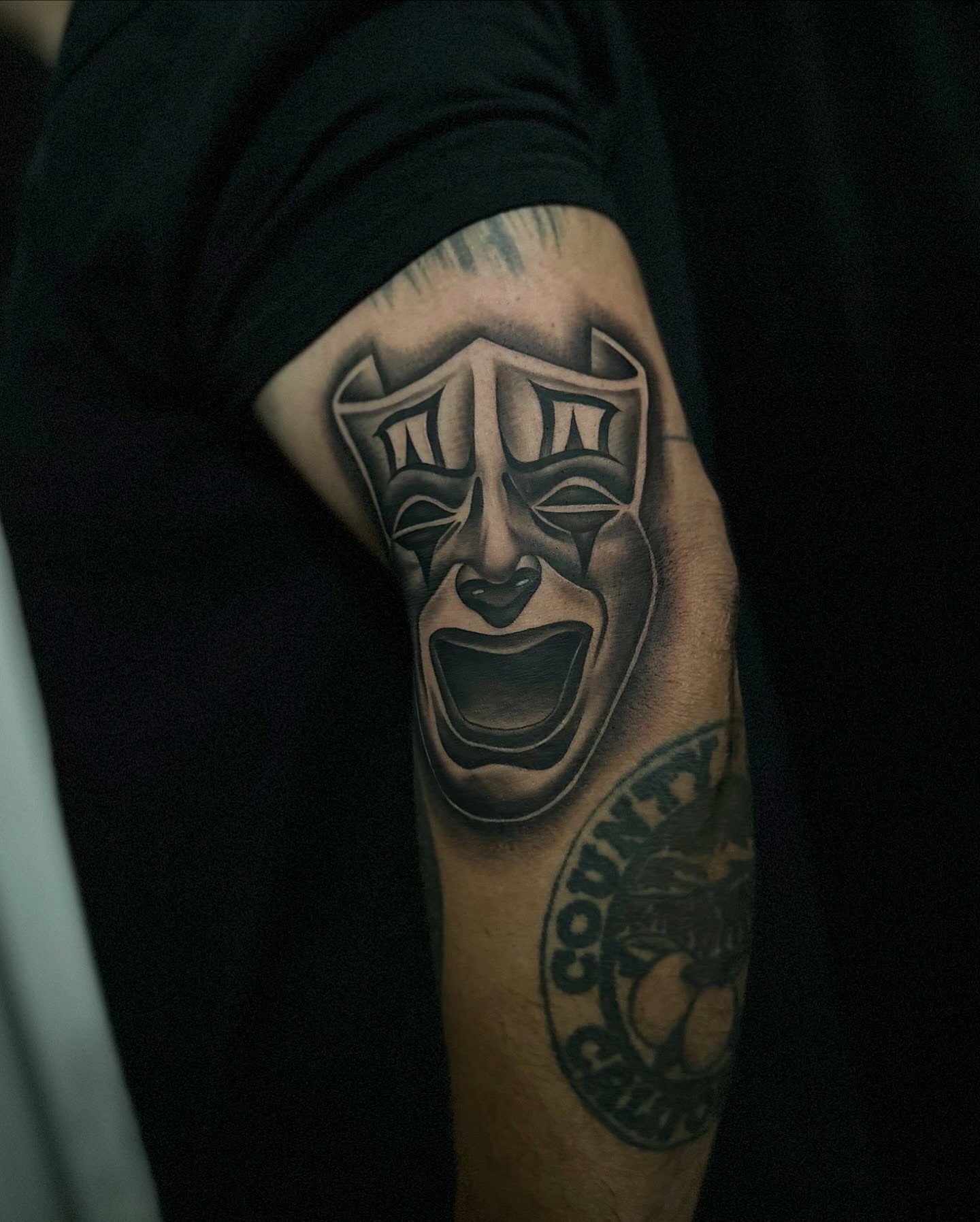 Theater masks black and grey tattoo on the forearm by Emma Sferdian🇷🇴