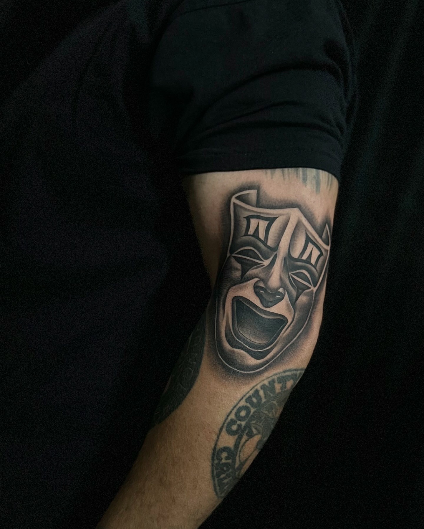 Theater masks black and grey tattoo on the forearm by Emma Sferdian🇷🇴