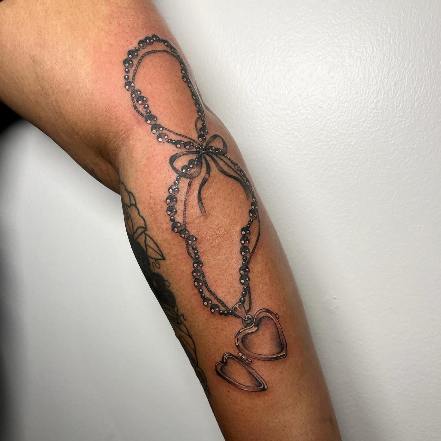 Necklace with heart pendants black and grey tattoo on the forearm by aurora