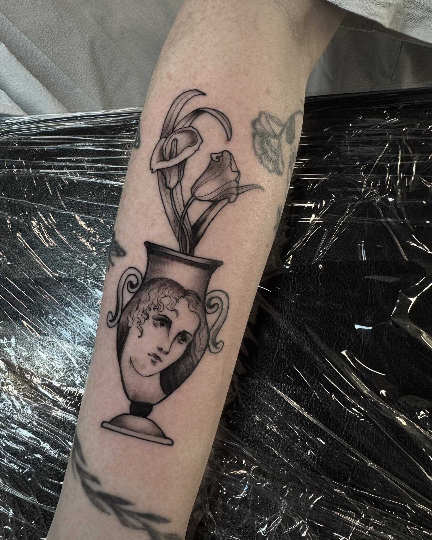 Vase with flowers black and grey tattoo on the forearm by Hannah Mckee