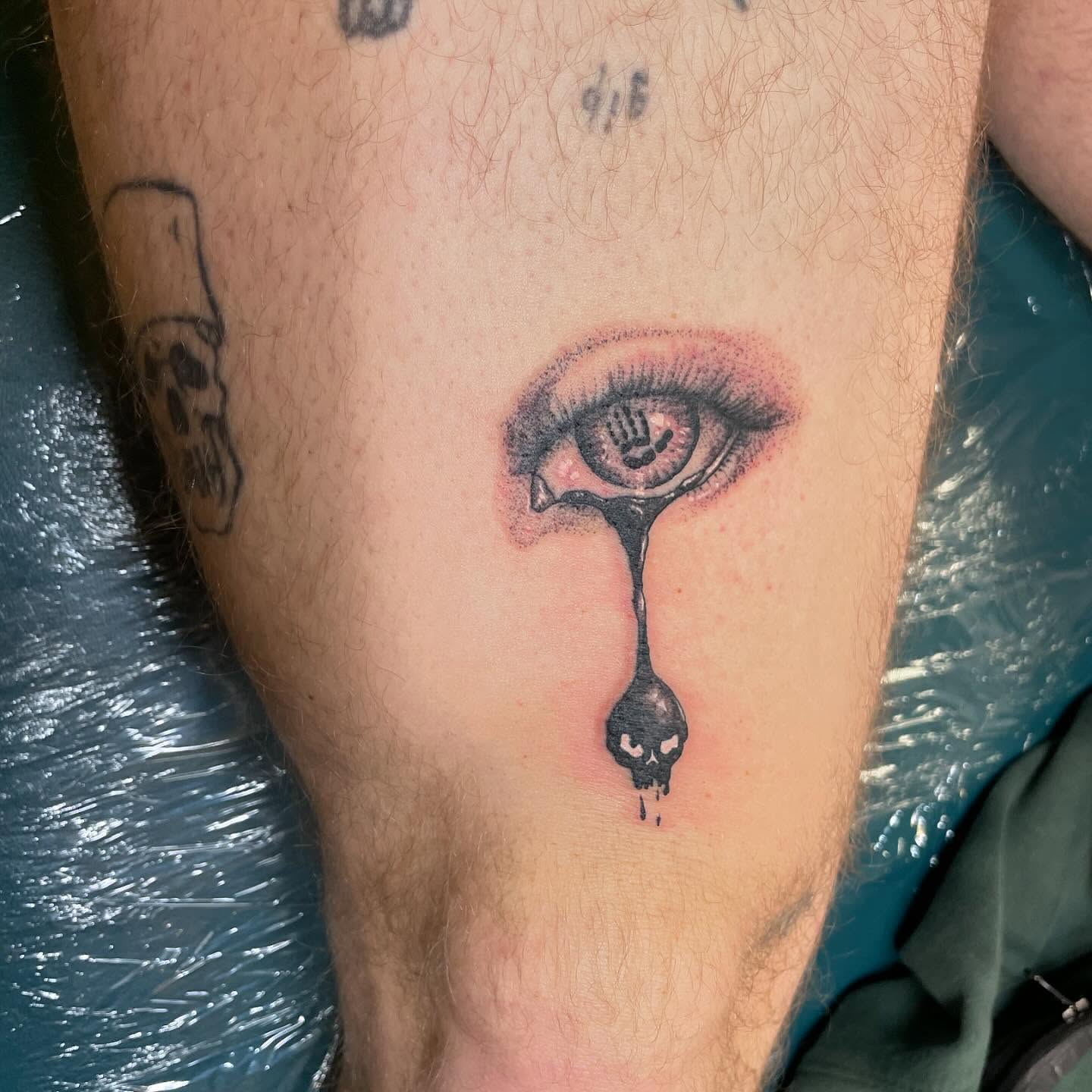 Eye with dripping skull dark realism tattoo on the thigh by Evan