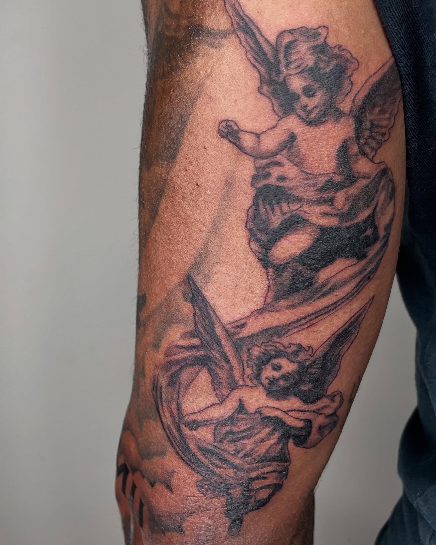 Cherubs black and grey tattoo on the forearm by Koolz